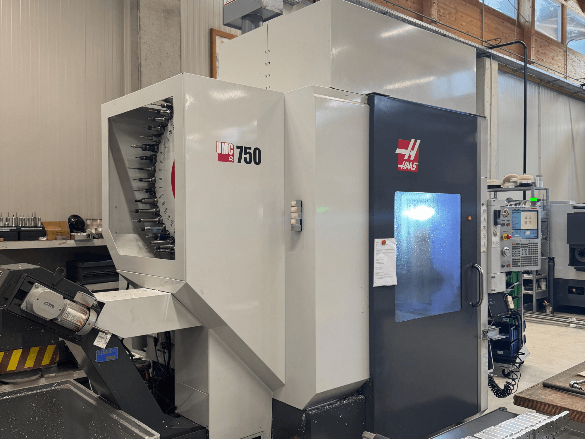 Haas UMC 750 bearbetningscenter, framifrån, visar verktygshållare och kontrollpanel i en verkstadsmiljö.
