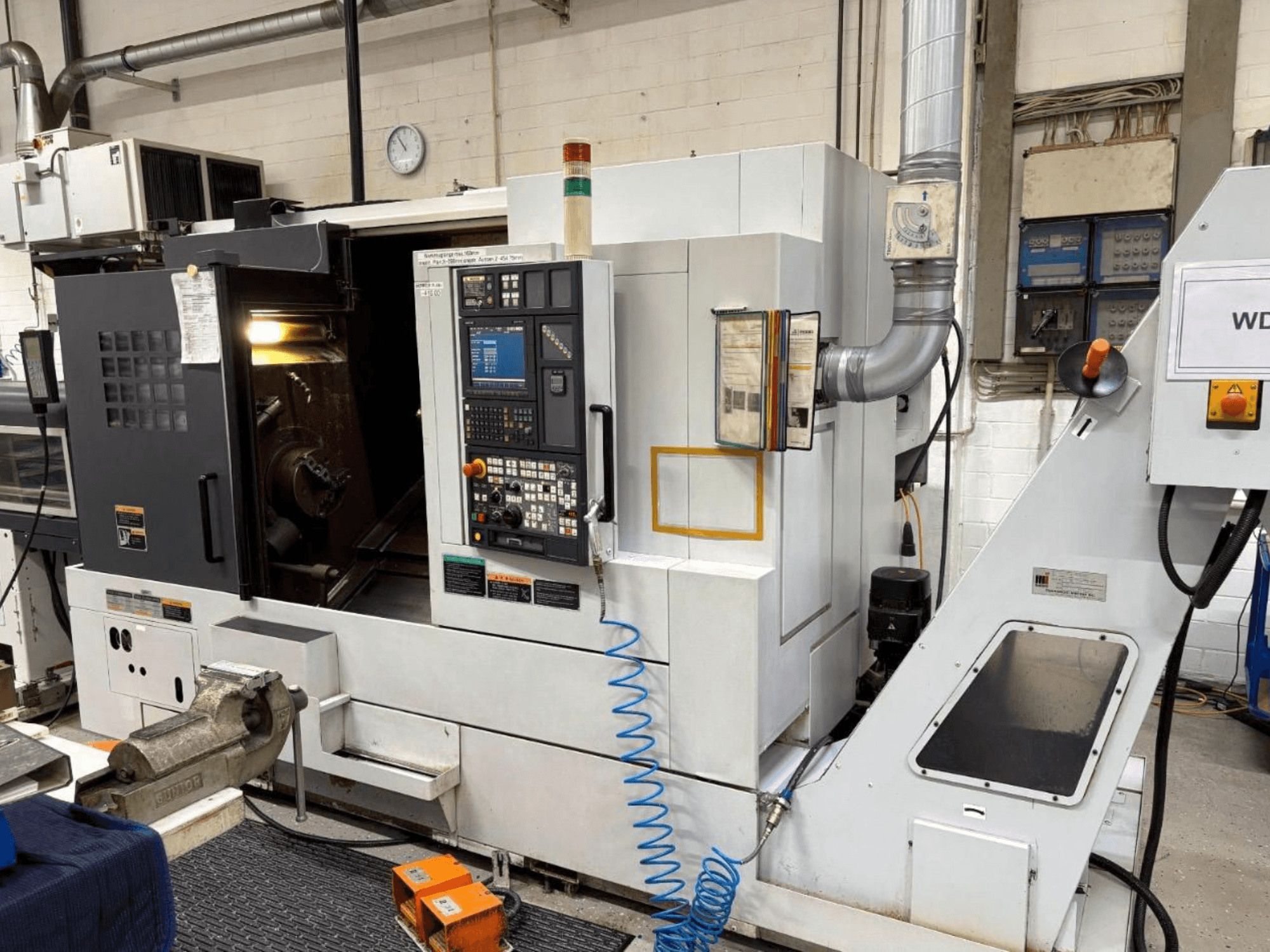 MORI SEIKI NL 2500 SY svarv- och fräscenter, vy framifrån, visar kontrollpanel och bearbetningsområde. Synligt kylvätskesystem och tillbehör.