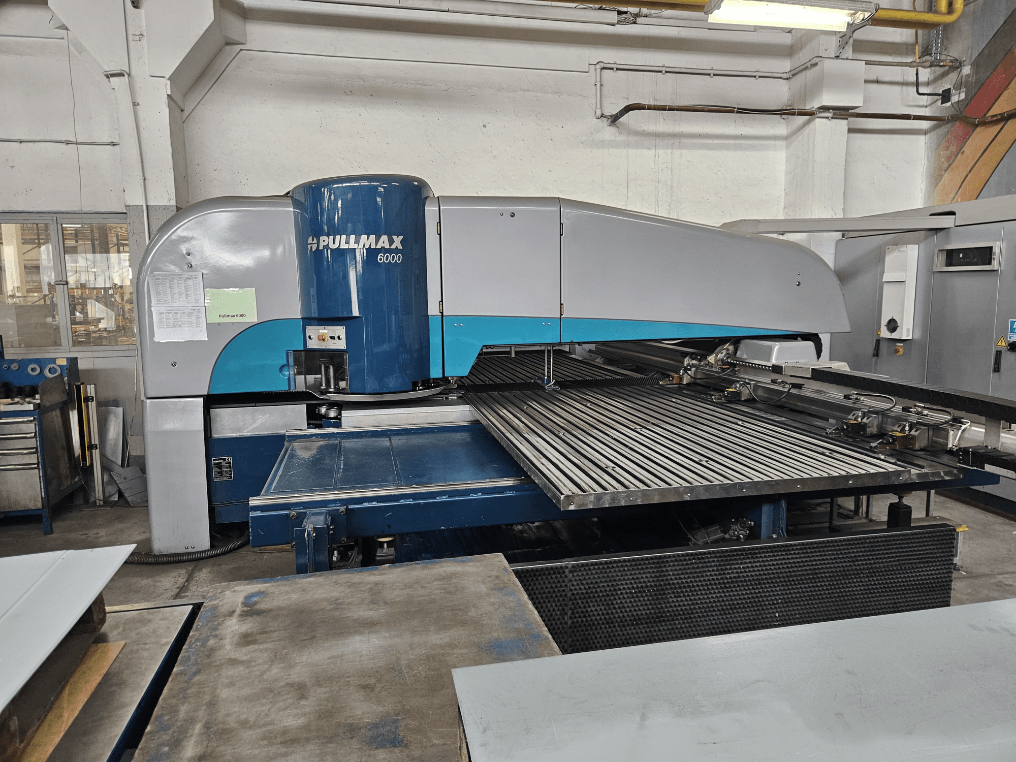 Frontvy av Pullmax 6000 CNC-stansmaskin, som visar upp sin stora flatbädd och metallram i en verkstadsmiljö.