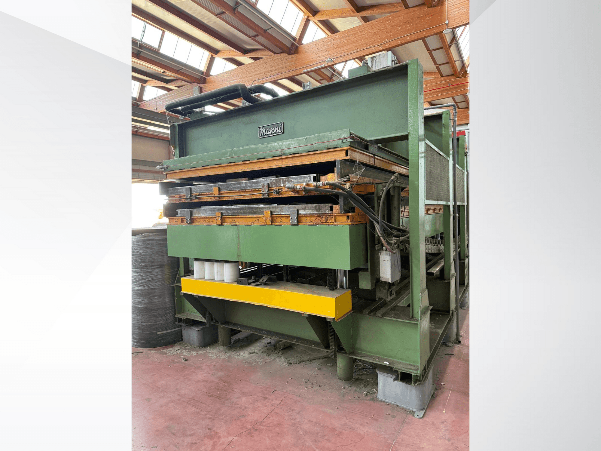 Manni hydraulisk press, vy från sidan, med grön metallkropp, gul bas och flera synliga hydraulledningar.