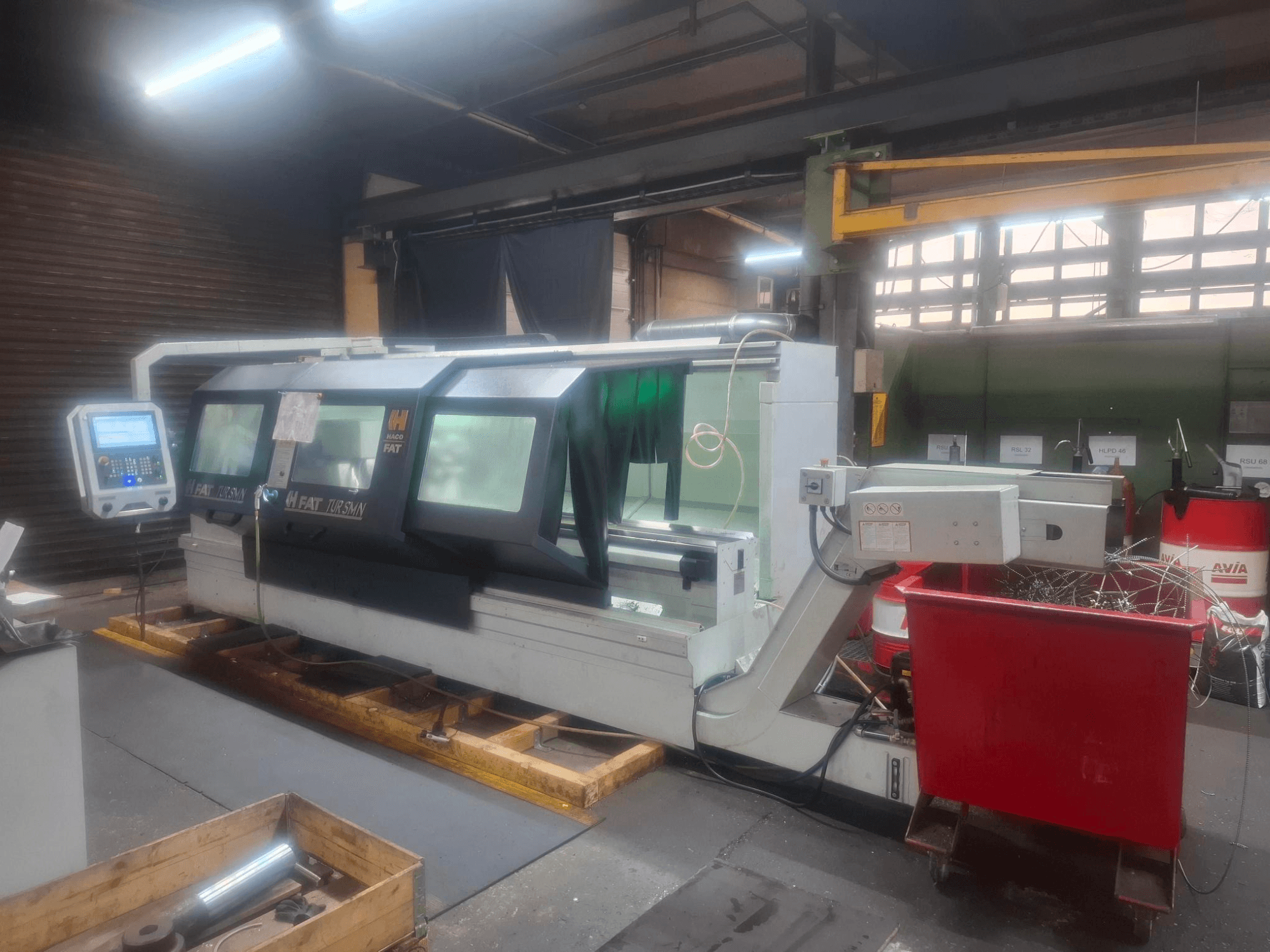Frontvy av en FAT Tursan CNC-maskin med kontrollpanel, placerad på träpallar i en verkstad.