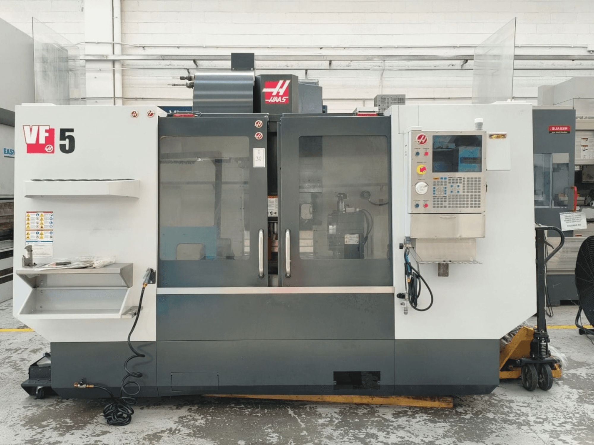 HAAS VF 5/40 vertikalt bearbetningscenter, framifrån sett, med kontrollpanel och glasdörrar.