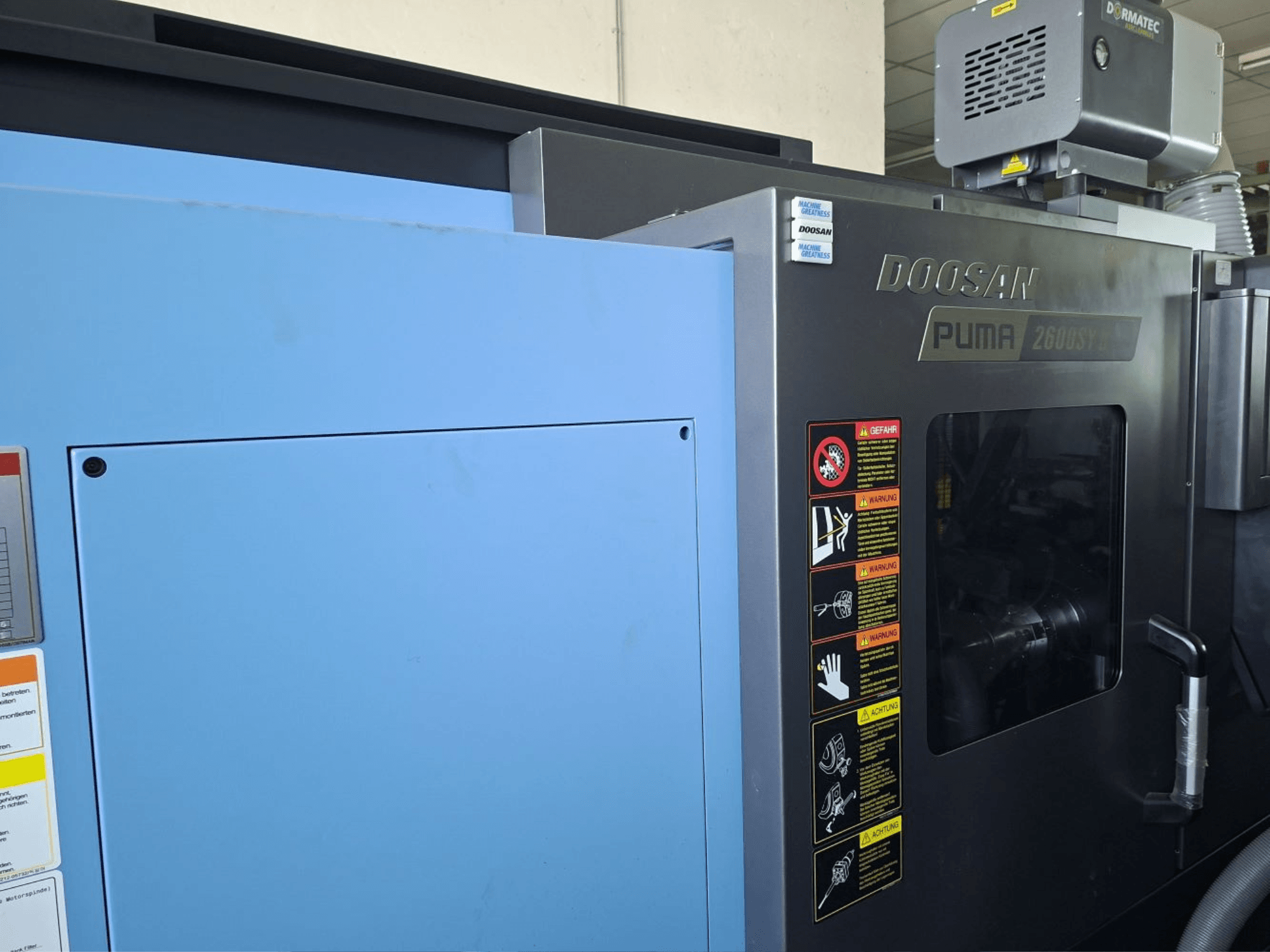 DOOSAN PUMA 2600 SY II horisontell svarv, framifrån, med säkerhetsetiketter och blå paneler.