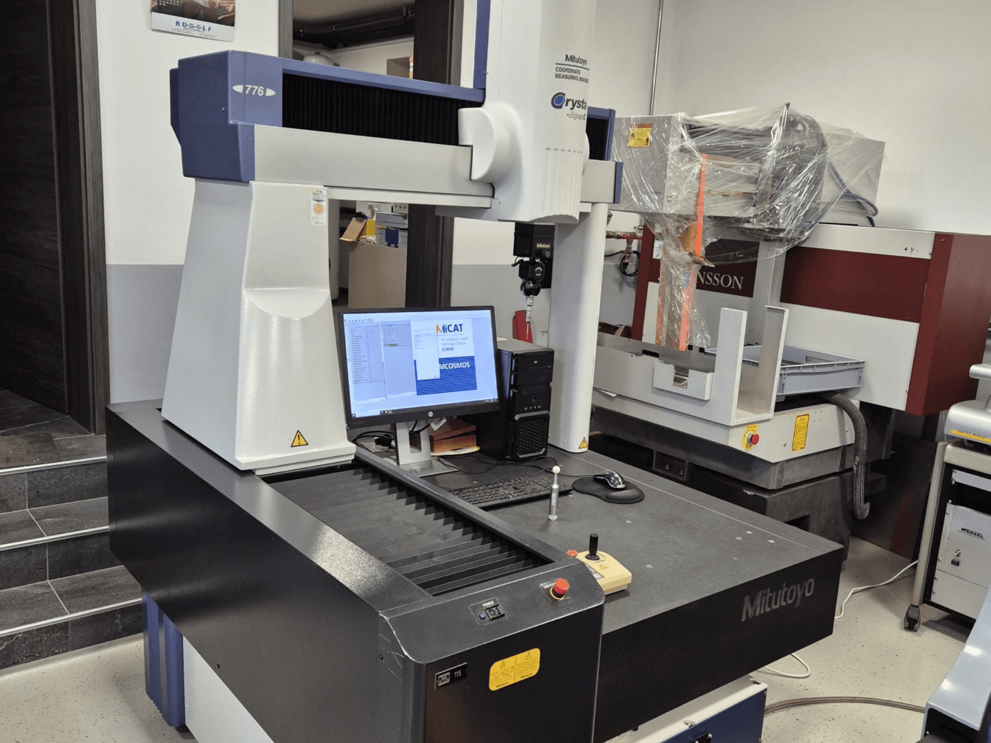 Koordinatmätmaskin Mitutoyo modell 776 framifrån, med en monitor som visar mätprogramvara och kontroller synliga.