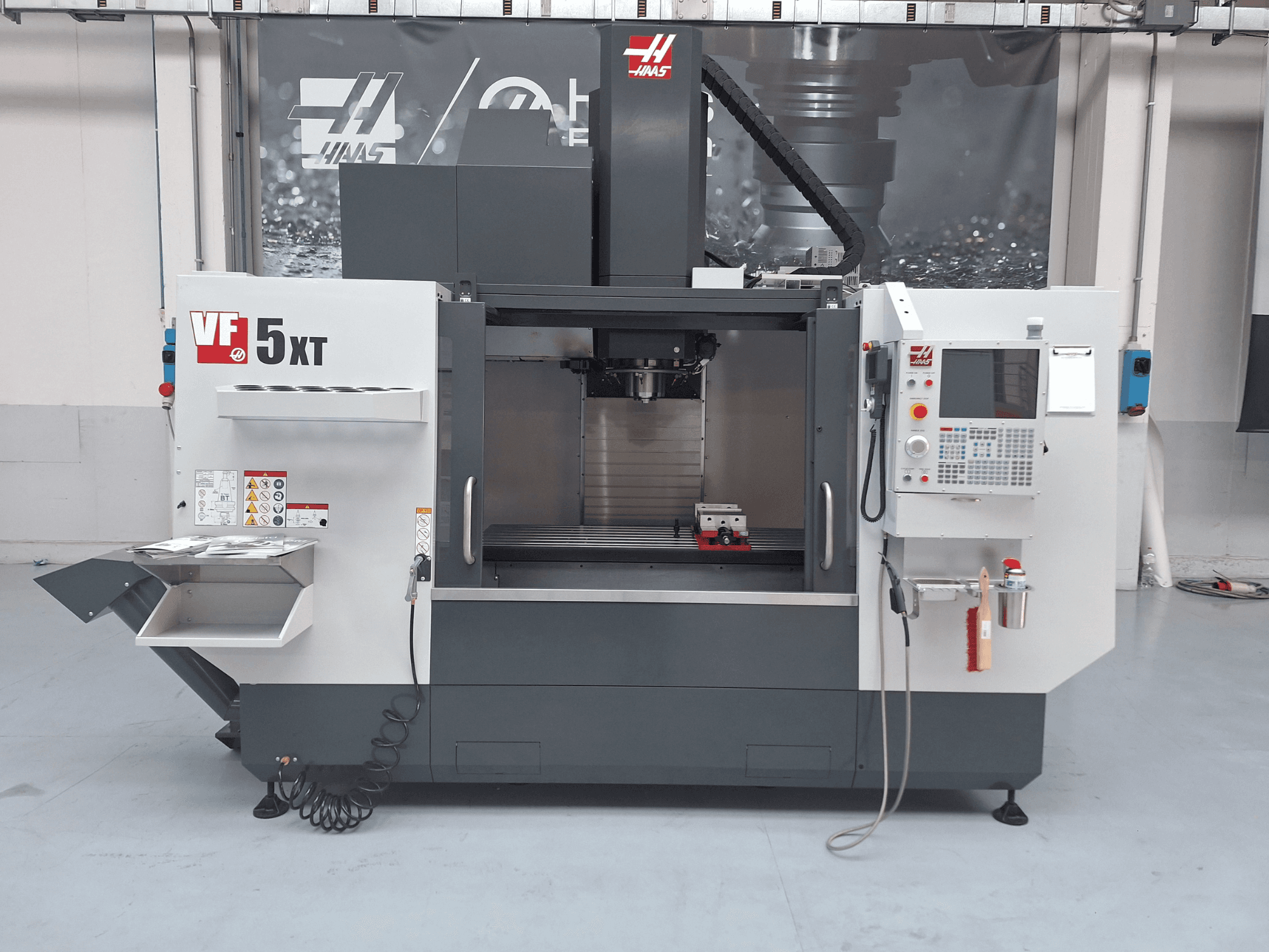 HAAS VF-5/50XT vertikalt bearbetningscenter, framifrån, med kontrollpanelen, spindeldelen och verktygsförvaringen i förgrunden.
