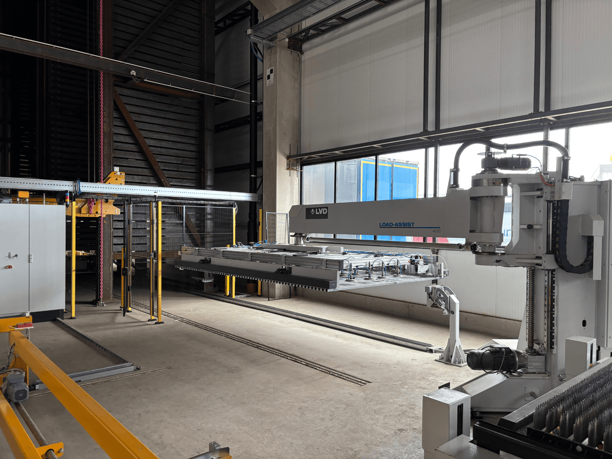 LVD Load-Assist 4020 automationsutrustning framifrån med en robotarm och lastningssystem synligt i ett stort arbetsutrymme.