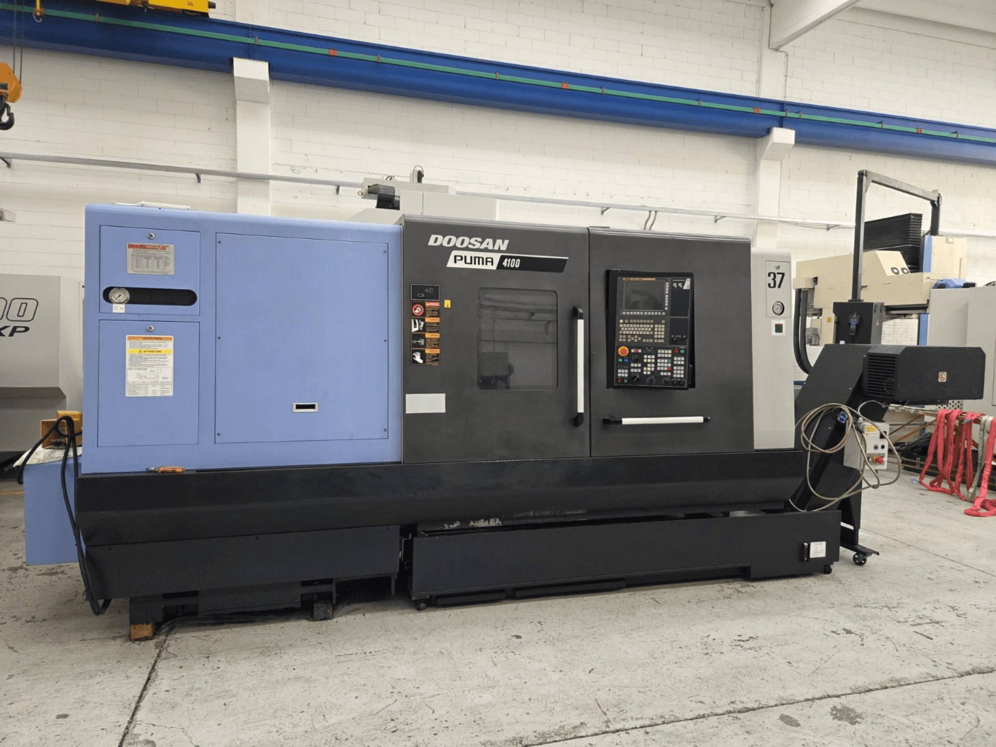 Doosan Puma 4100 CNC-svarv, framifrån; har kontrollpanel, blå kraftenhet och detaljerade etiketter för driftvägledning.