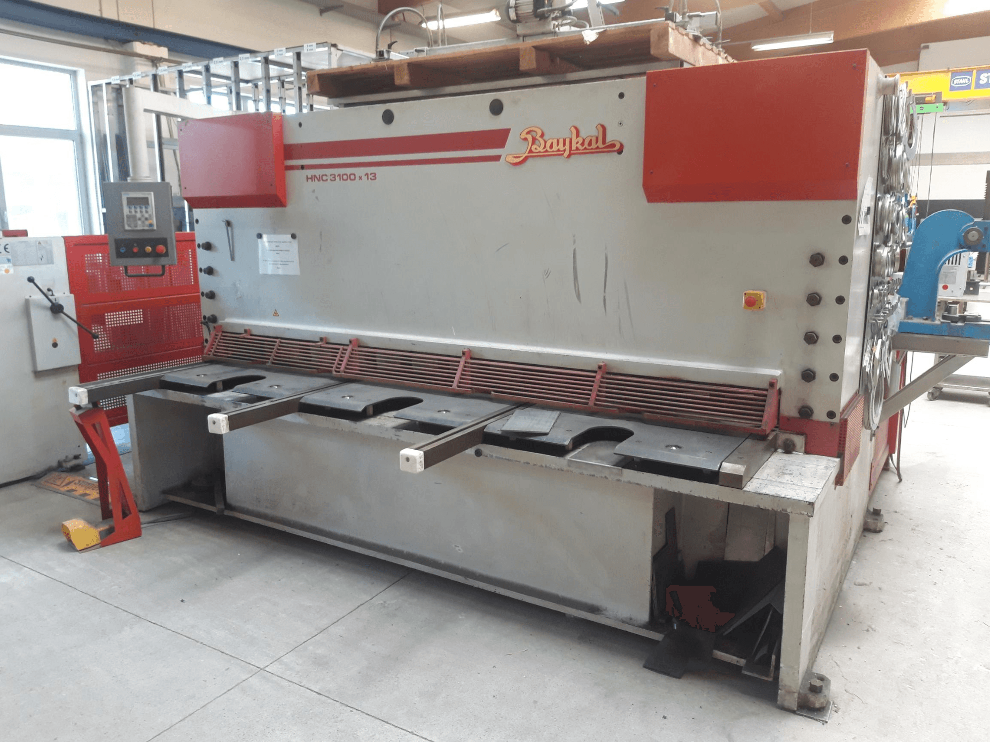 Baykal HNC 3100x13 CNC-skärmaskin, framifrån, med kontrollpanel, skärområde för metall och utrymme för uppsamling av avfall.