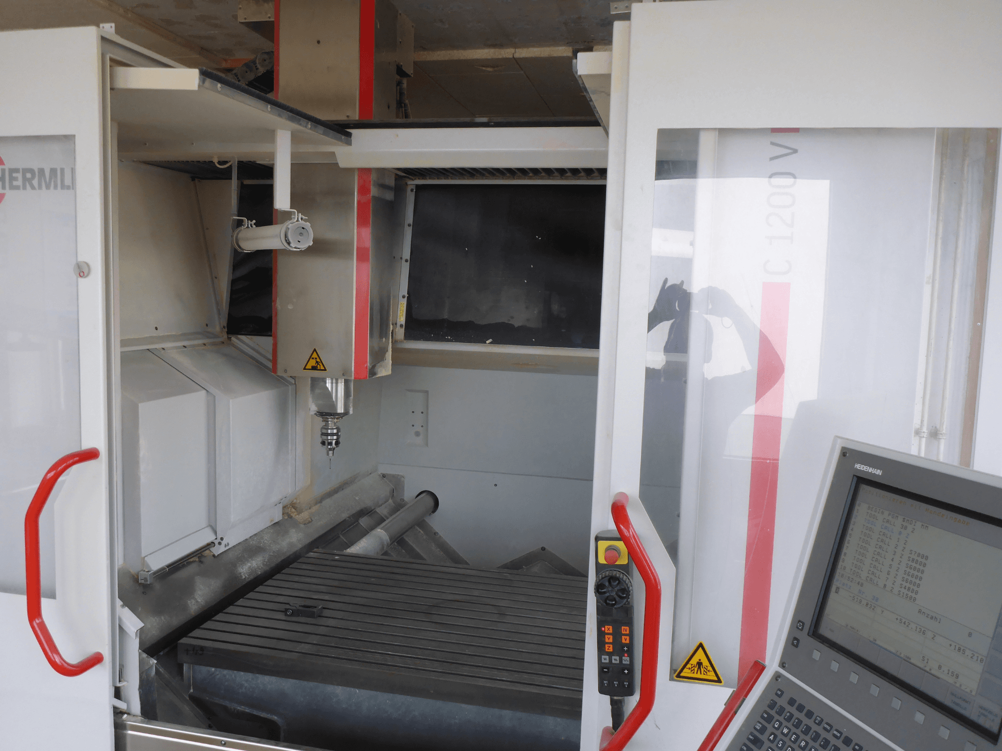 HERMLE C 1200 vertikal fleroperationsmaskin med verktygshållare, kontrollpanel och arbetsbord framifrån.