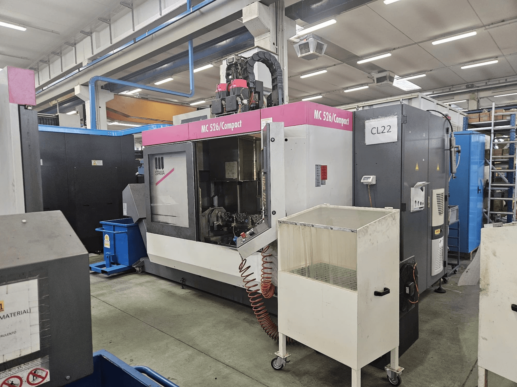 MC 526 Compact CNC-maskin från Stama, sidovy, visar kontrollpanel, kylvätsketank och intilliggande maskiner.