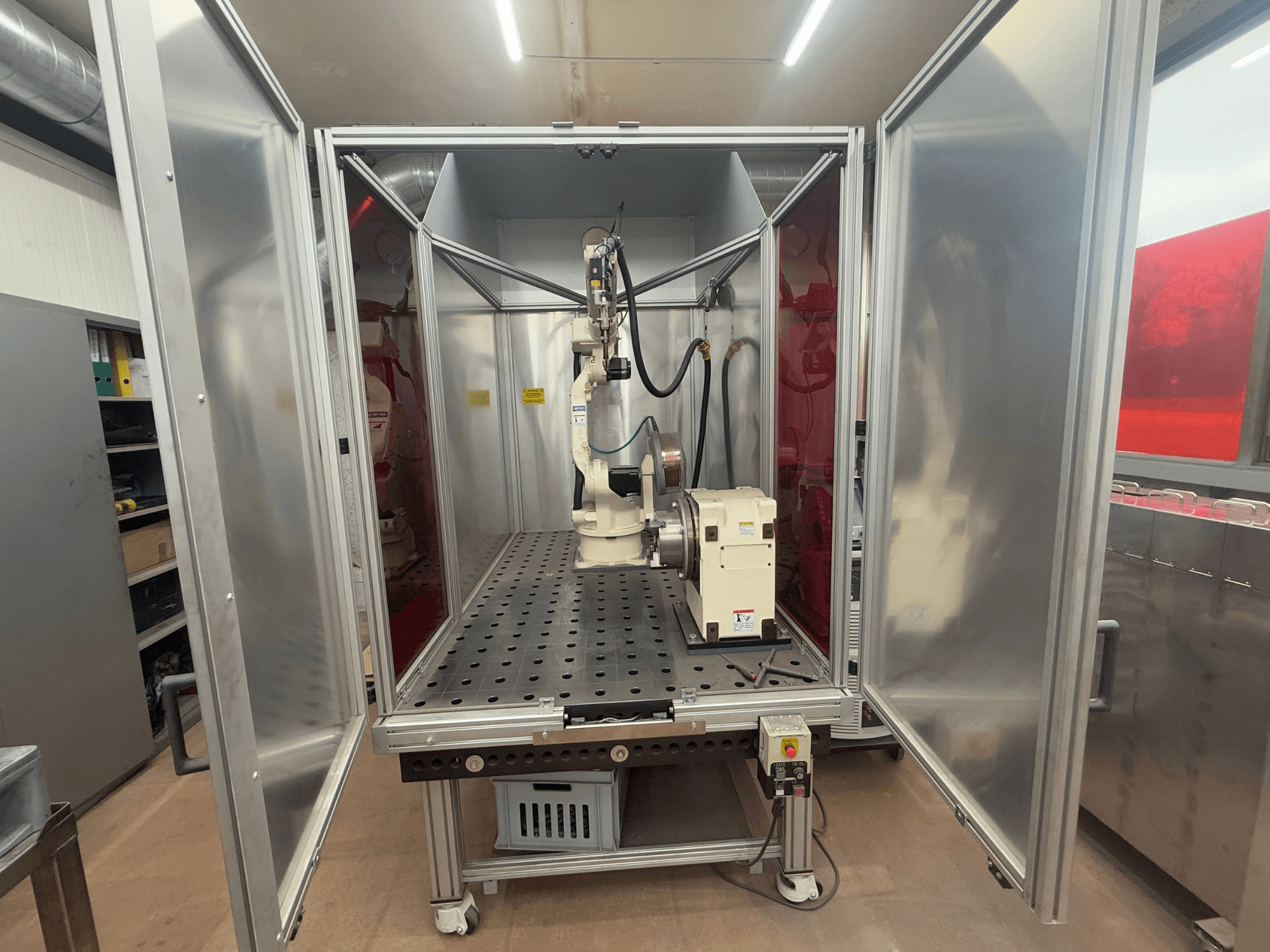 Svetsrobot OTC Daihen EASY ARC V02.04 i metallkapsling, sedd framifrån, med ledad arm och kontrollpanel.