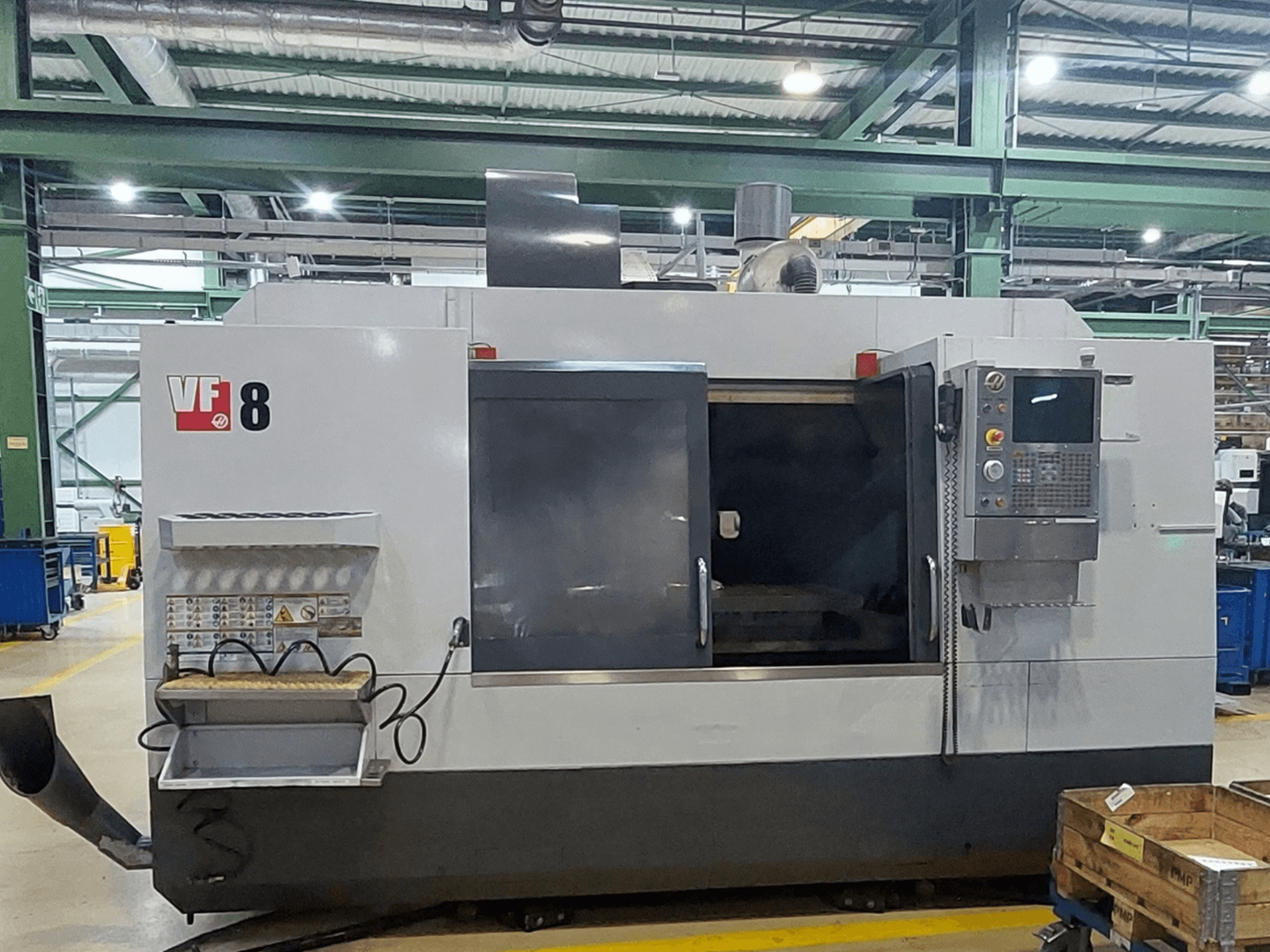 HAAS VF-8 vertikalt bearbetningscenter, framifrån; med kontrollpanel och lastningsområde, utformat för precisa bearbetningsuppgifter.
