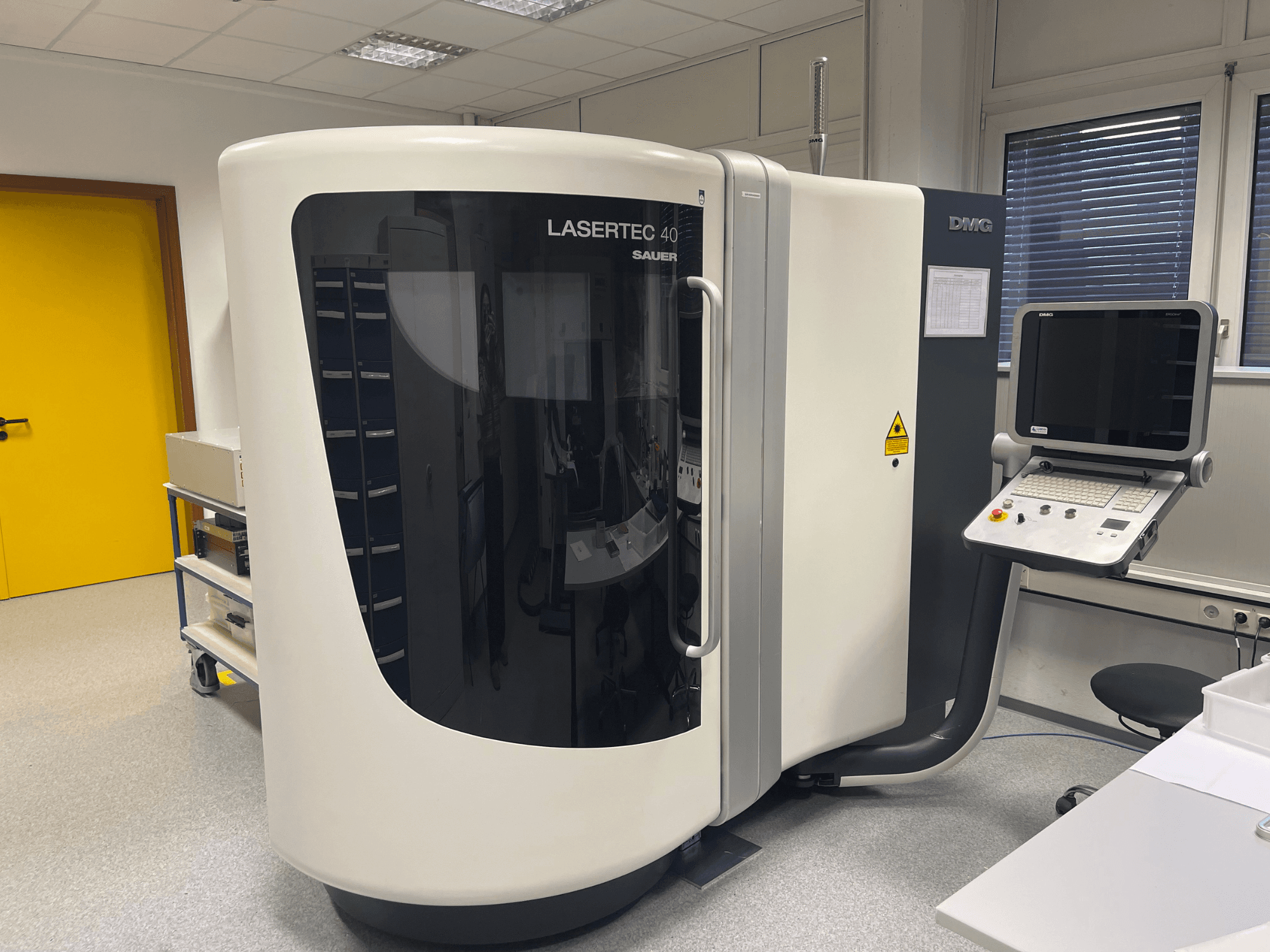 Vit LASERTEC 40 fräsmaskin från DMG MORI, framifrån, med kontrollpanel och ergonomisk design i ett väl upplyst rum.