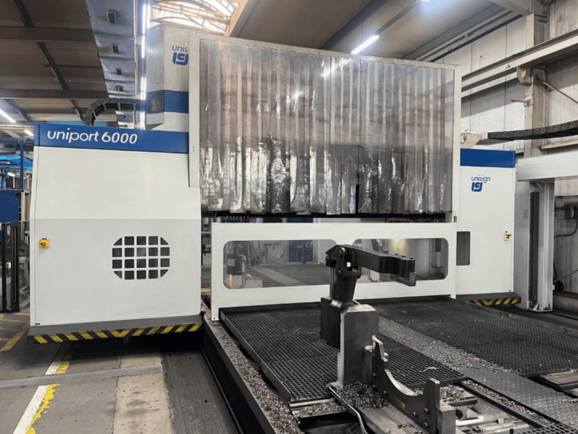 Portalfräsmaskin Unisign uniport 6000, vy framifrån, visar maskinens struktur och skärområdet med metallspån.