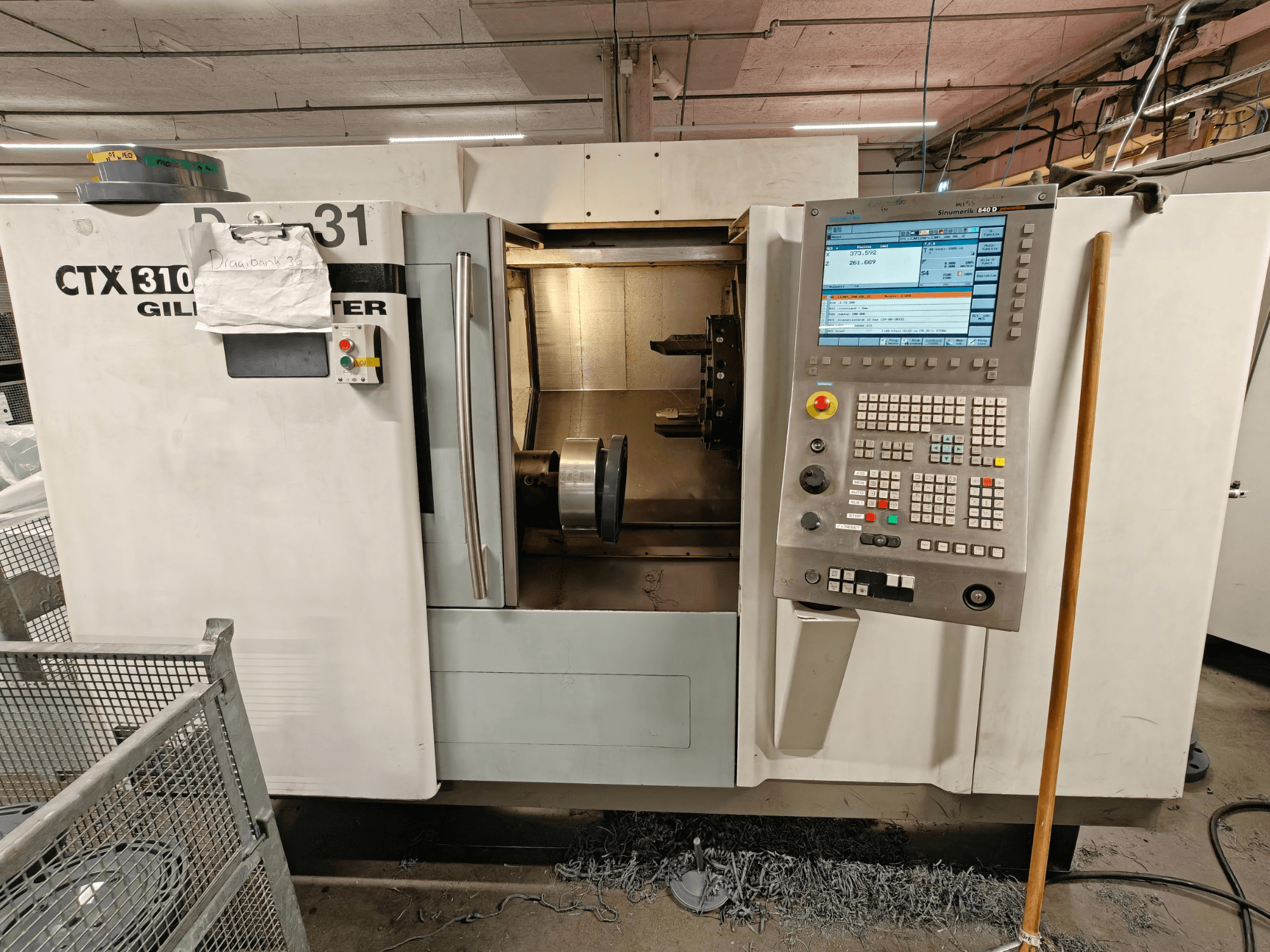 Gildemeister CTX 310 horisontell svarv, framifrån med kontrollpanel, visar verktyg och arbetsutrymme inuti.