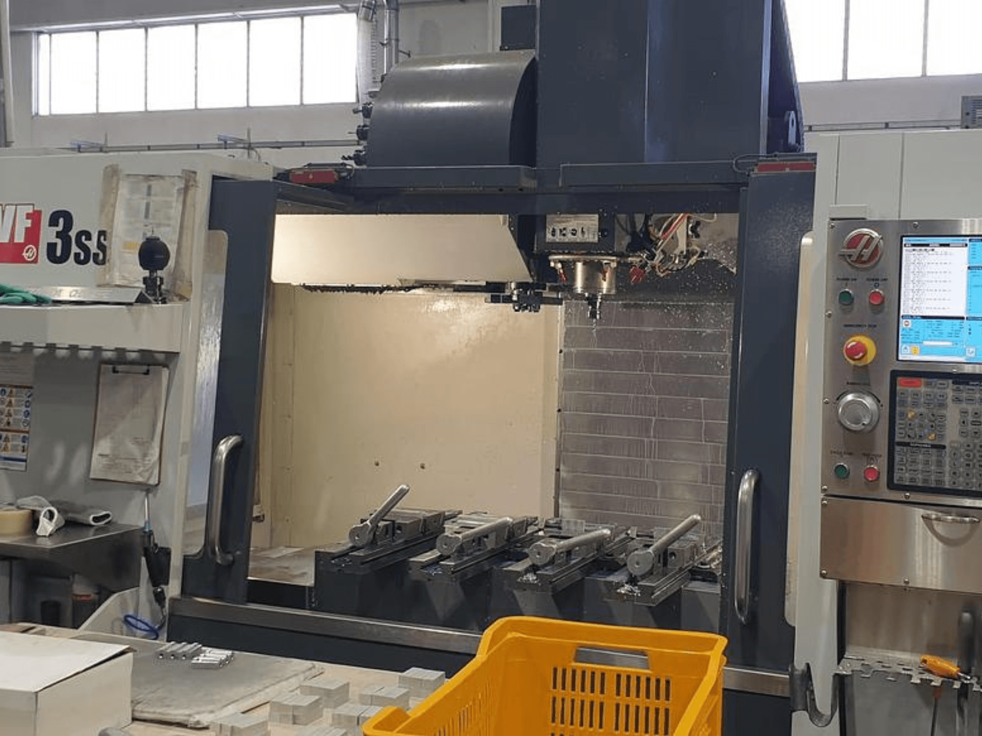 HAAS VF-3SS vertikalt bearbetningscenter, framifrån med CNC-kontrollpanel, verktyg och orange korg.