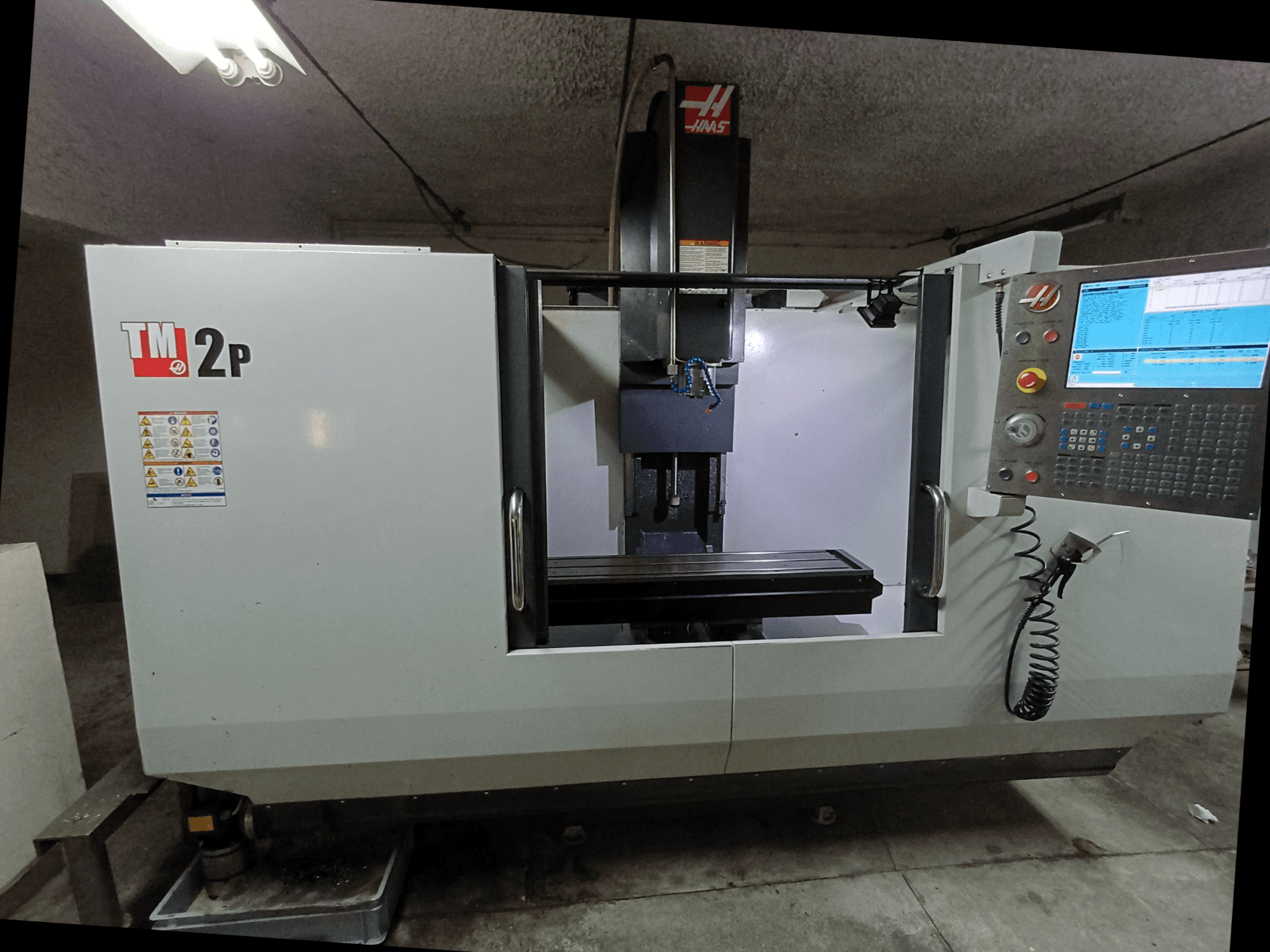 HAAS TM-2P vertikal fleroperationsmaskin, framifrån med kontrollpanel, spindelhuvud och maskinbädd.