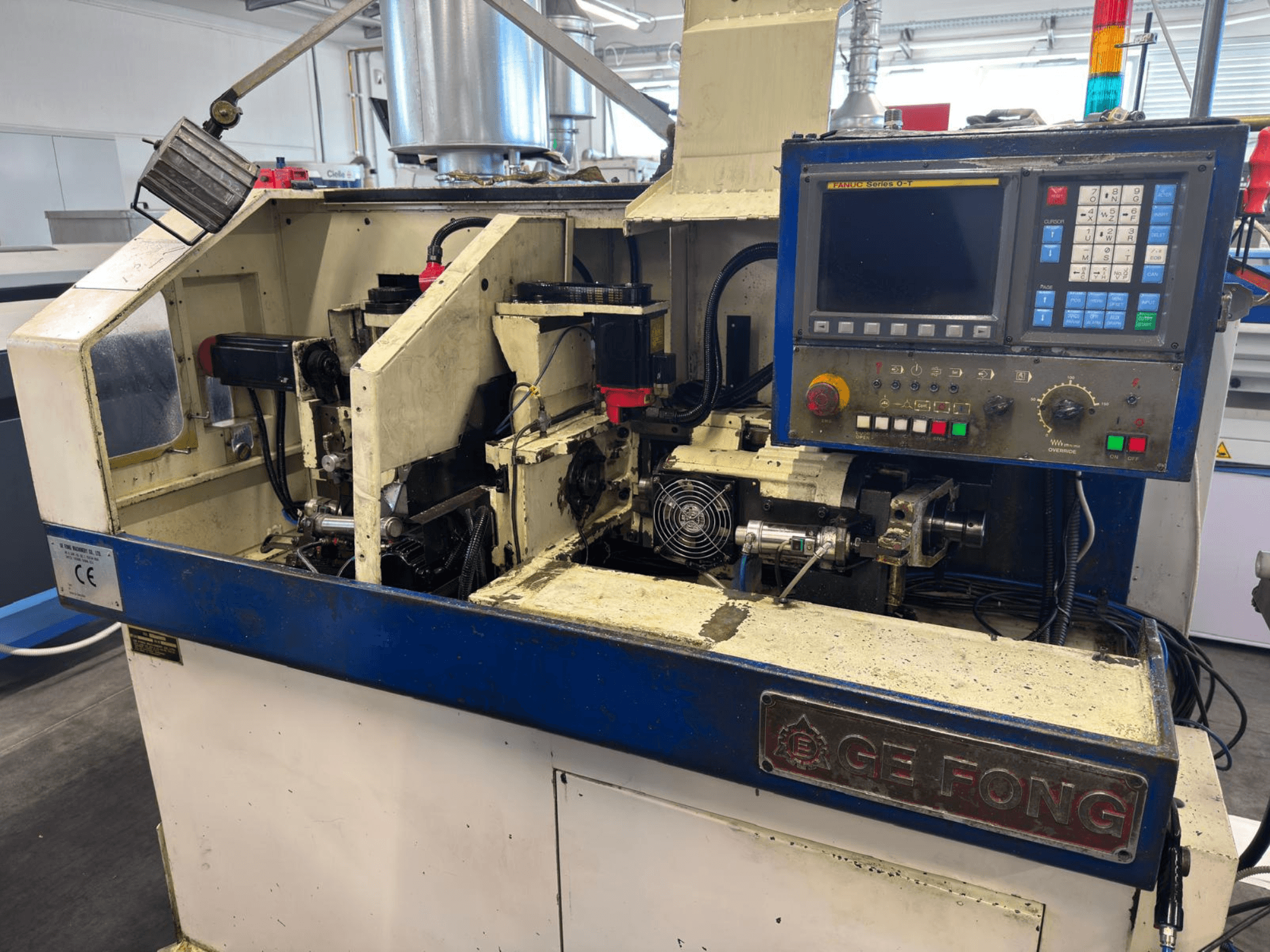 GE FONG industrimaskin i framifrånvy, visar interna komponenter, kontrollpanel och operativa delar.