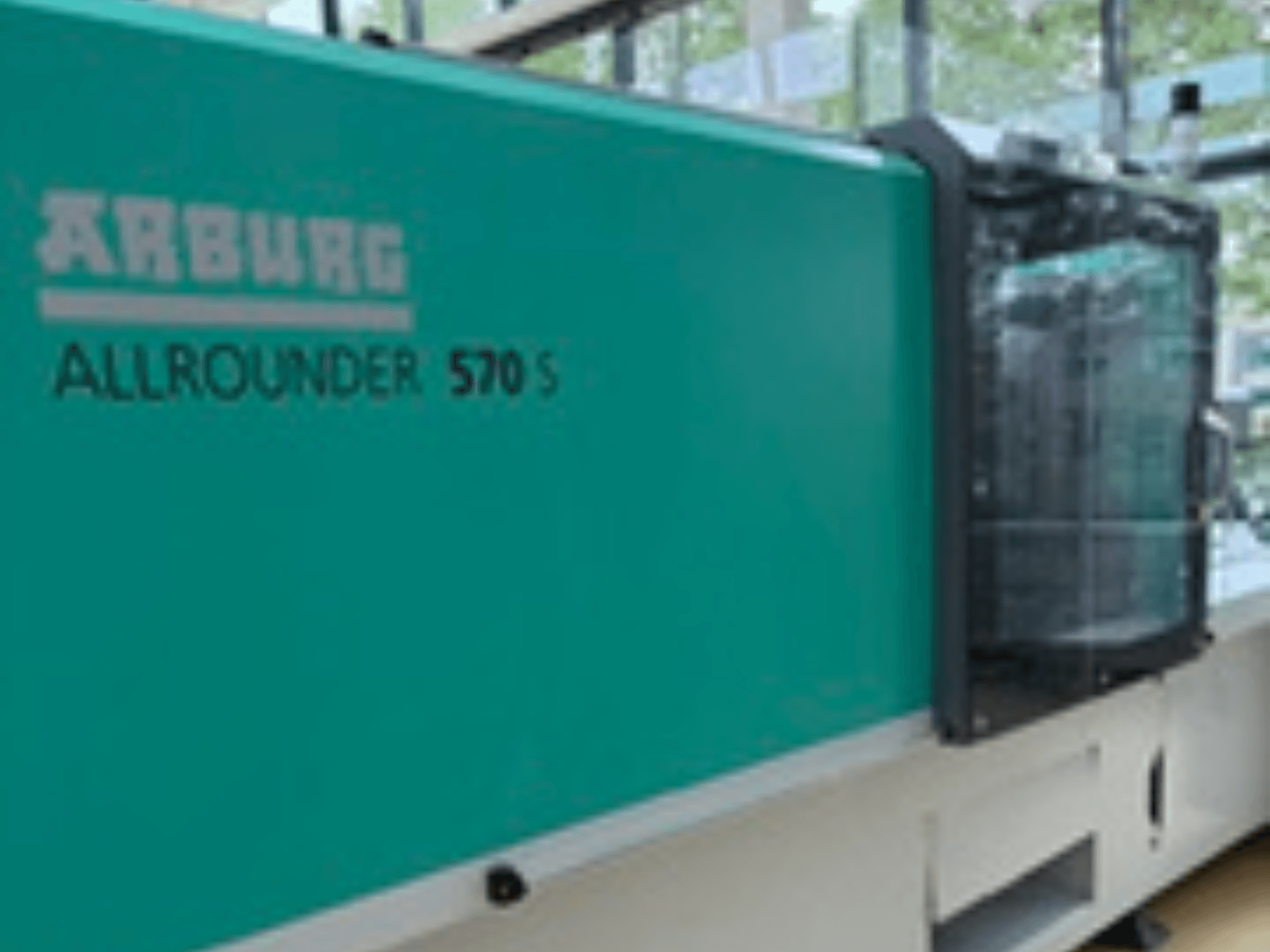 Frontvy av Arburg ALLROUNDER 570 S 1600-290, med tealfärgad exteriör och insprutningsenhet, som visar en del av maskinens design.