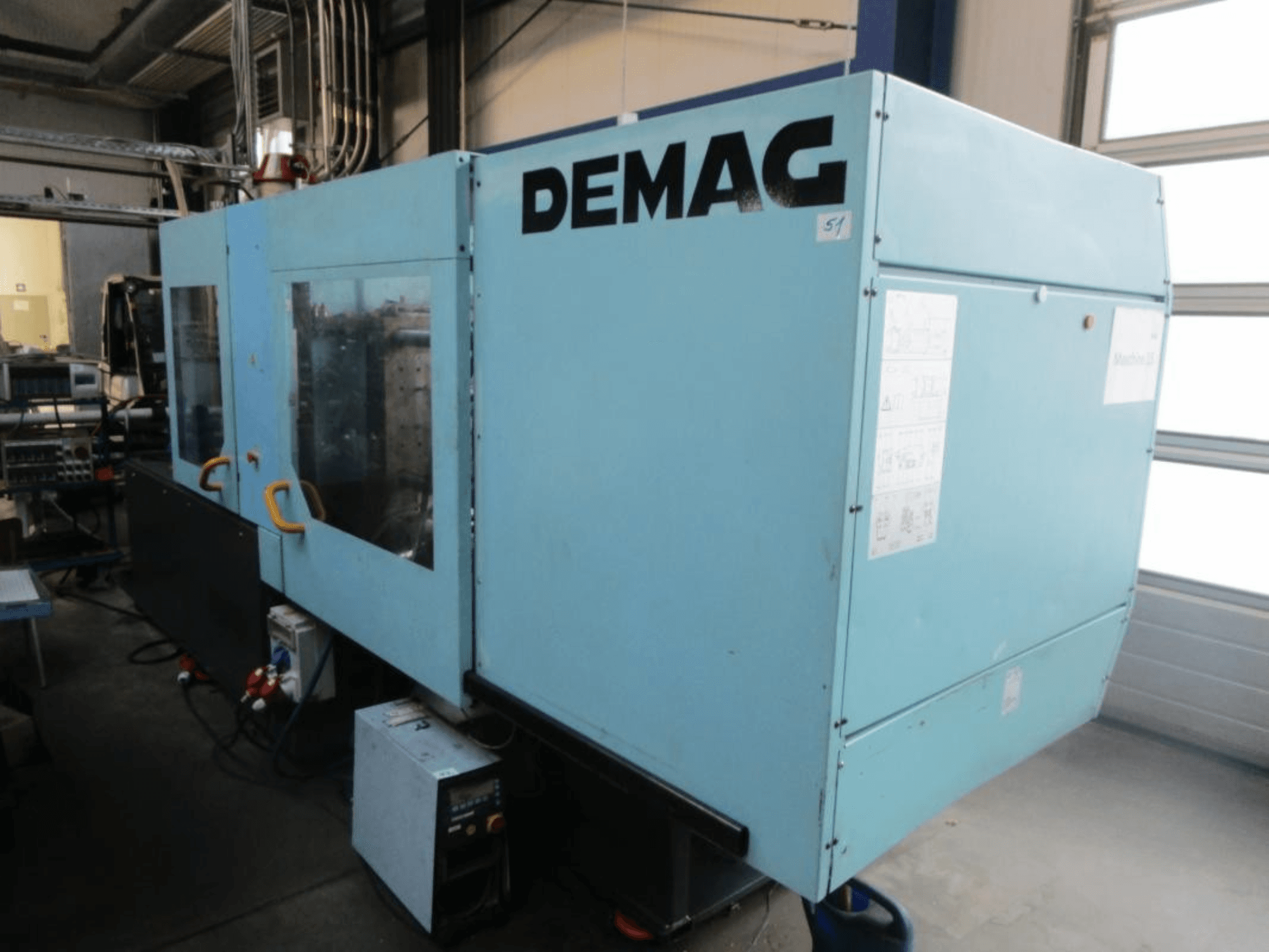 Framifrån sett på en hydraulisk formsprutningsmaskin av typen DEMAG Ergotech 150-610 Viva, med synlig kontrollpanel och handtag.