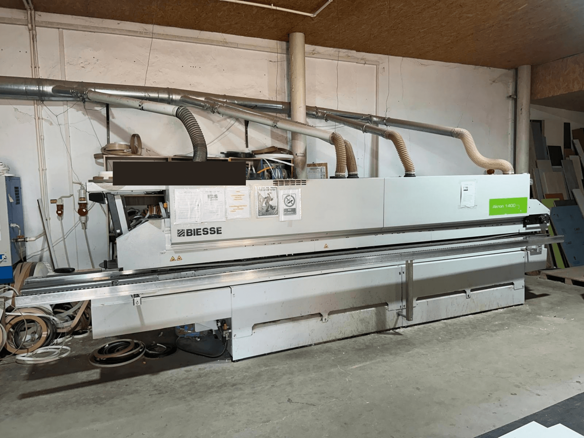 En BIESSE AKRON 1440 A kantlistmaskin, sett framifrån, med synlig manöverpanel och dammutsugskomponenter i en verkstadsmiljö.