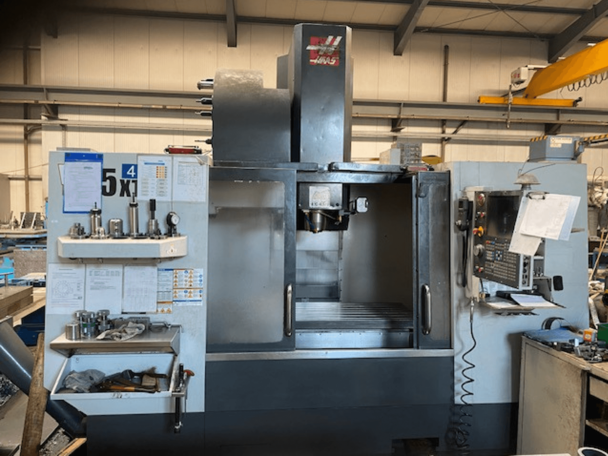 Haas VF-5 vertikala fleroperationsmaskin, framifrån, visar kontrollpanelen, verktygsförvaringen och spindelområdet.