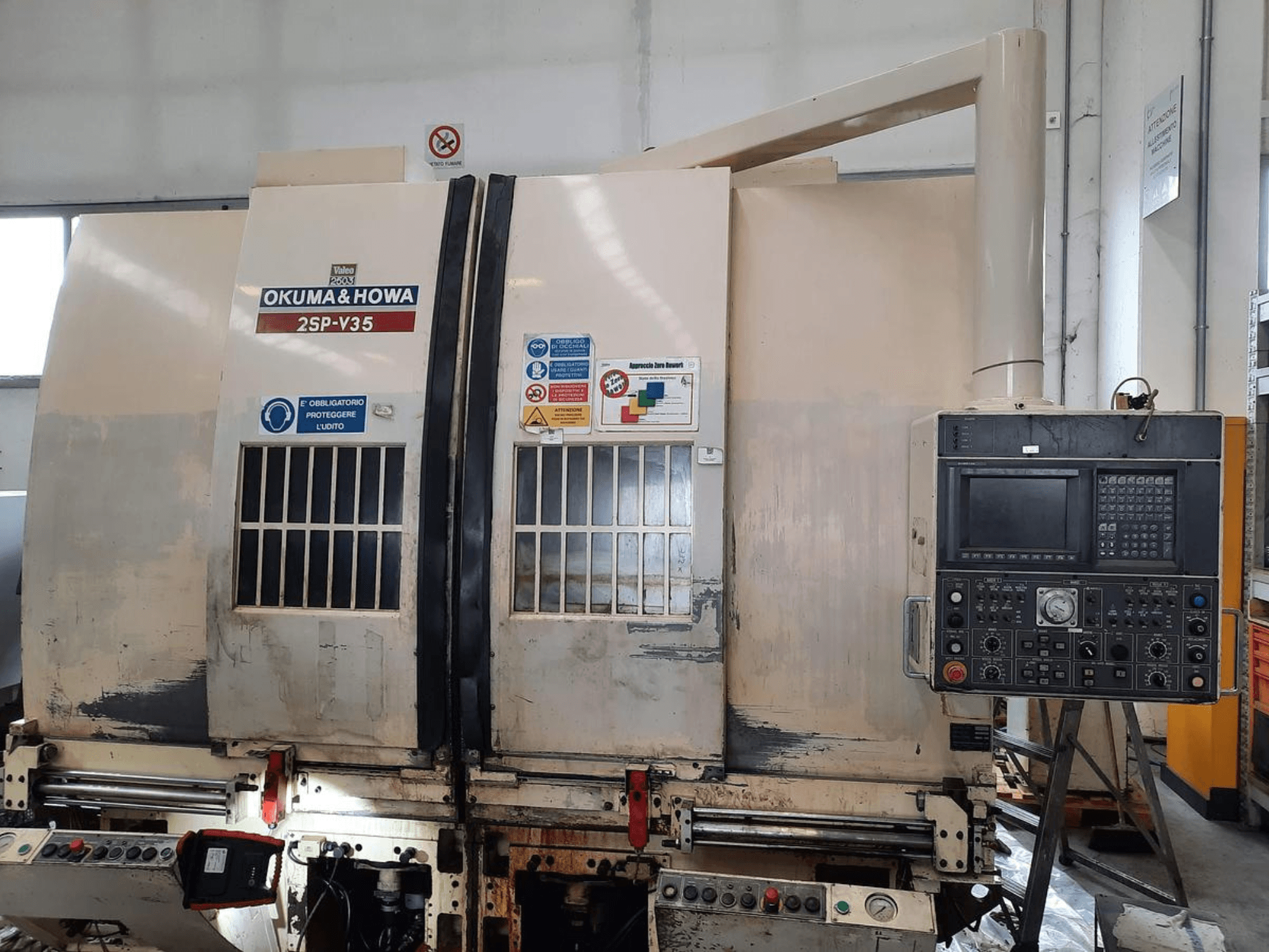 OKUMA & HOWA 2SP-V35 CNC-maskin sedd framifrån, med kontrollpanel med olika knappar och säkerhetsetiketter.