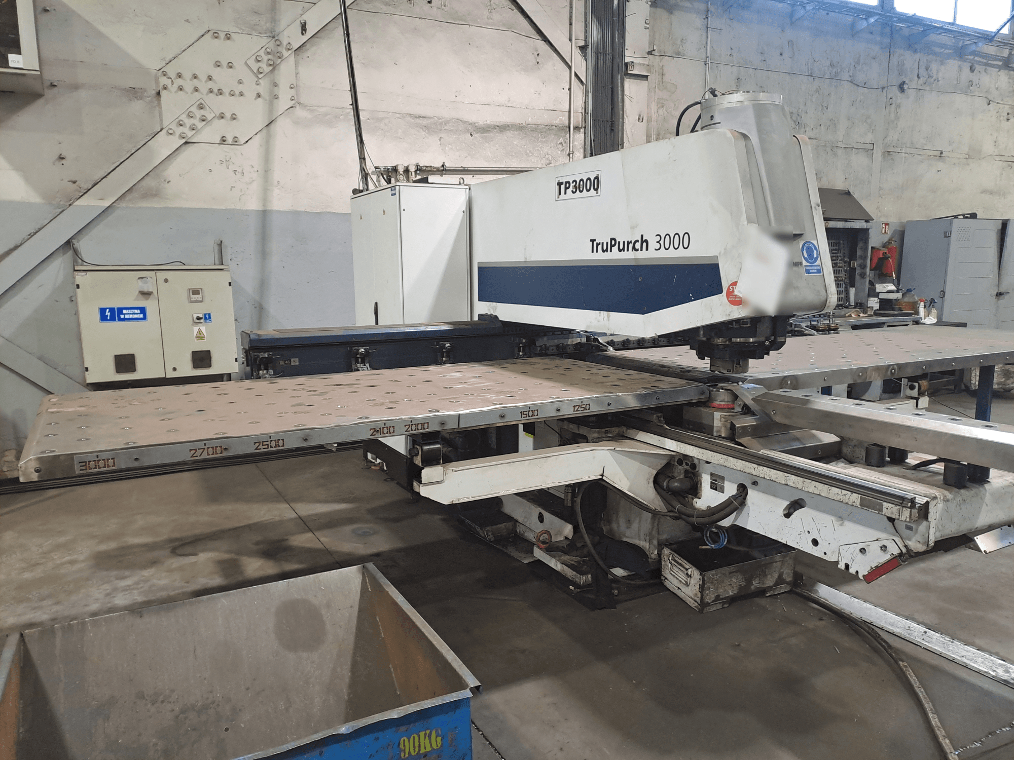 CNC-maskinen TruPunch 3000 framifrån, med en stor metallplatta och mätmarkeringar, i en industrimiljö.