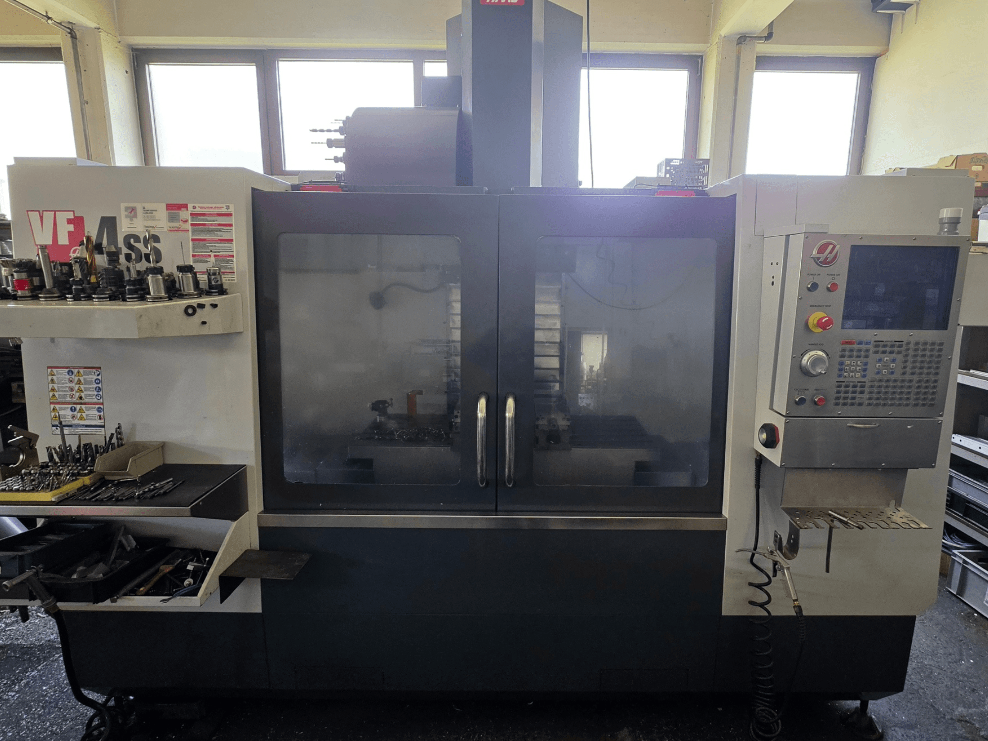 HAAS VF 34SS vertikal fleroperationsmaskin framifrån, med kontrollpanel och verktygsförvaring.