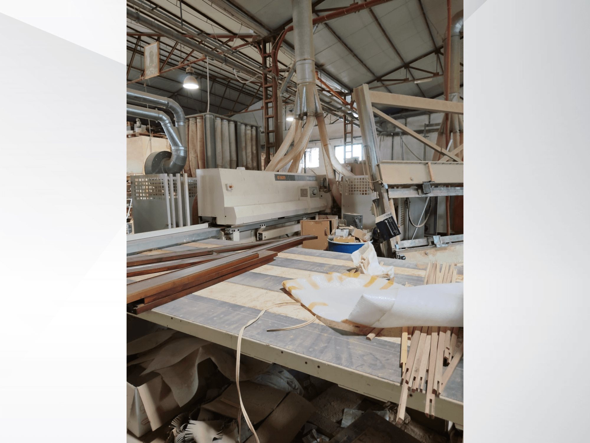 CNC-bearbetningscenter för trä SCM Windor60 i en verkstad, sedd från sidan med träpaneler och dammutsugningsutrustning.