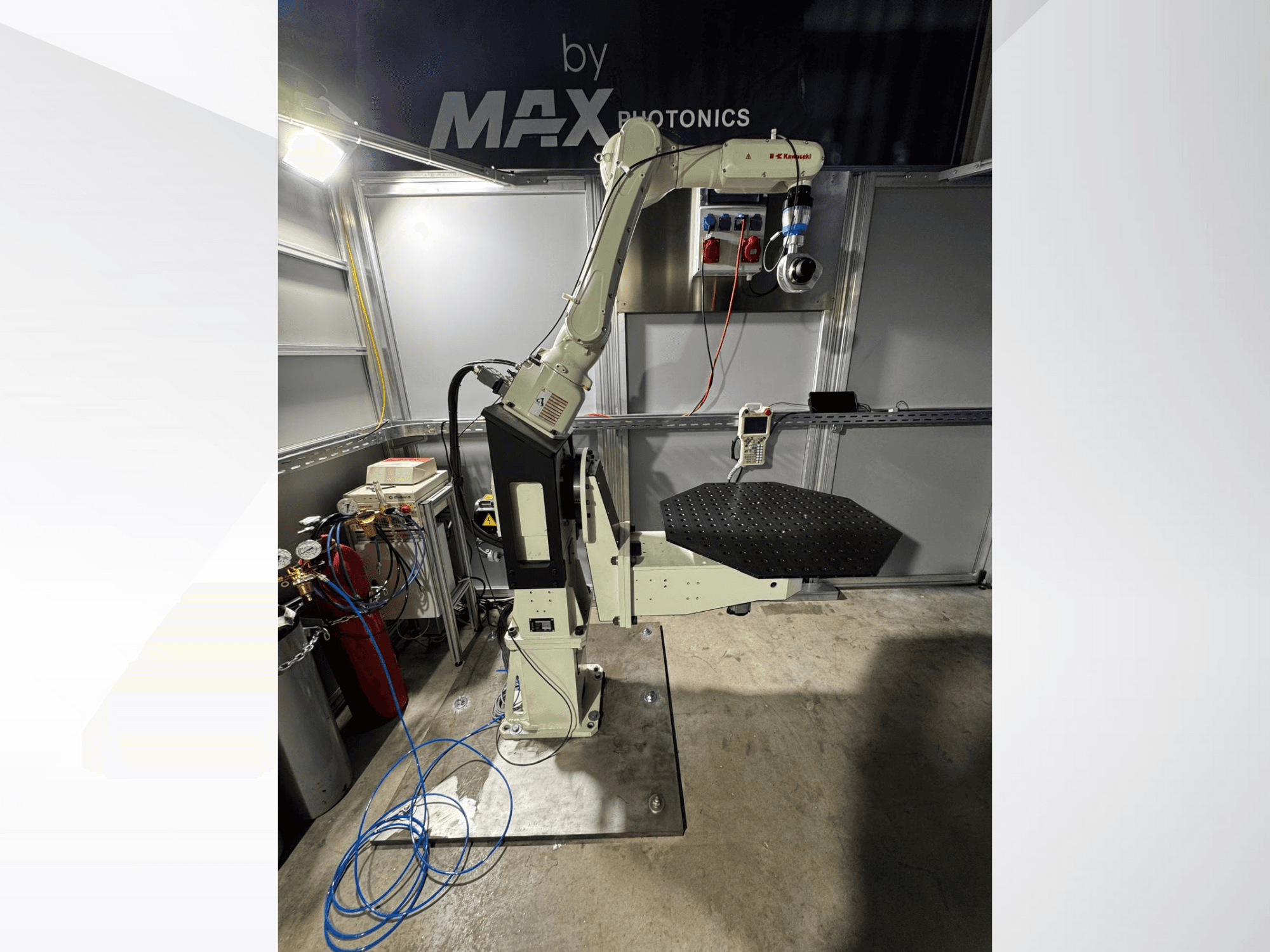 Max Photonics robotarmsapparat, framifrån, med svart perforerad plattform och kontrollpanel med mätare och kablar.