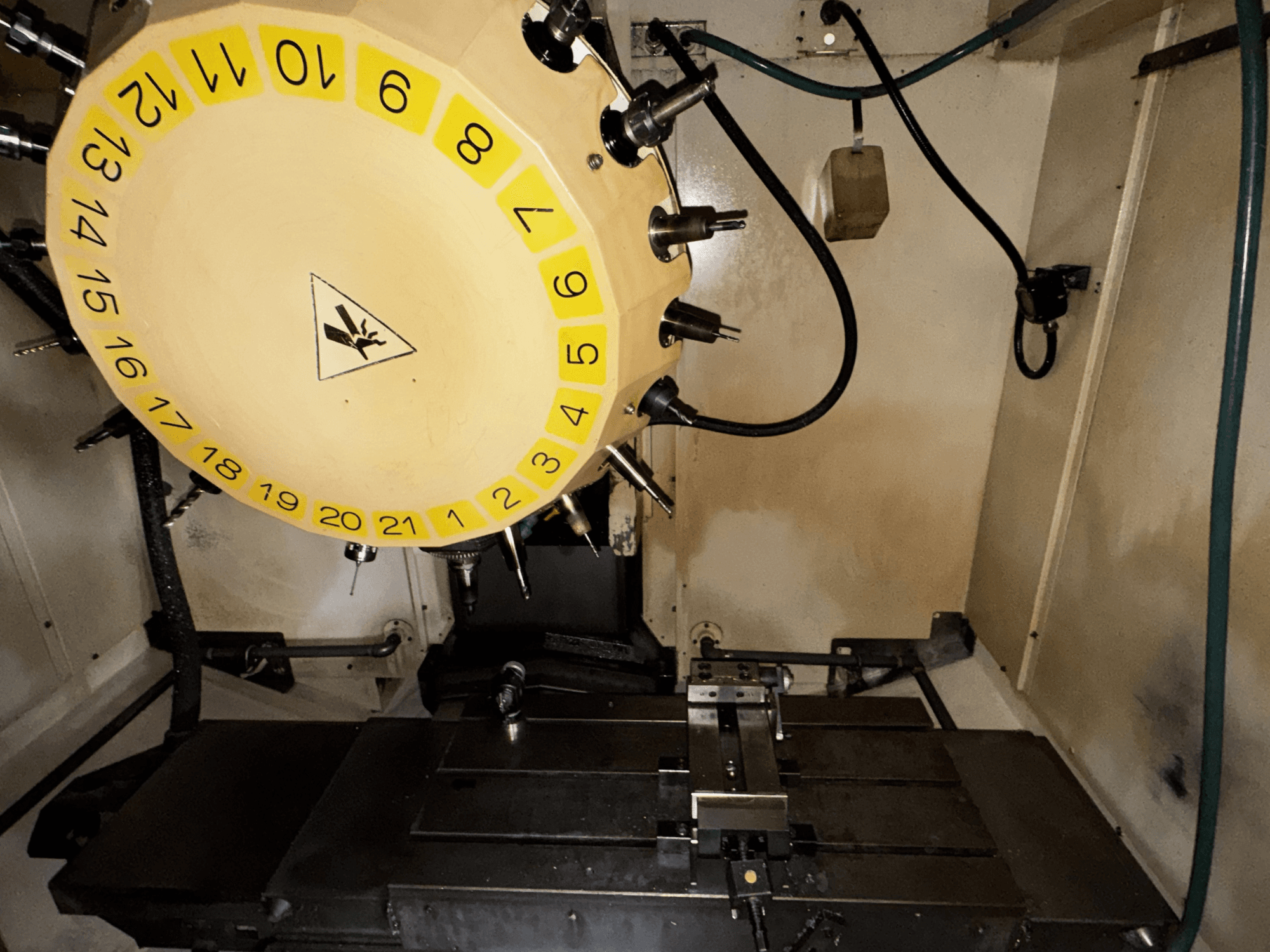 FANUC Robodrill alpha-T21iFL vertikal fleroperationsmaskin inifrån med verktygskarusell och bearbetningsbord synliga.