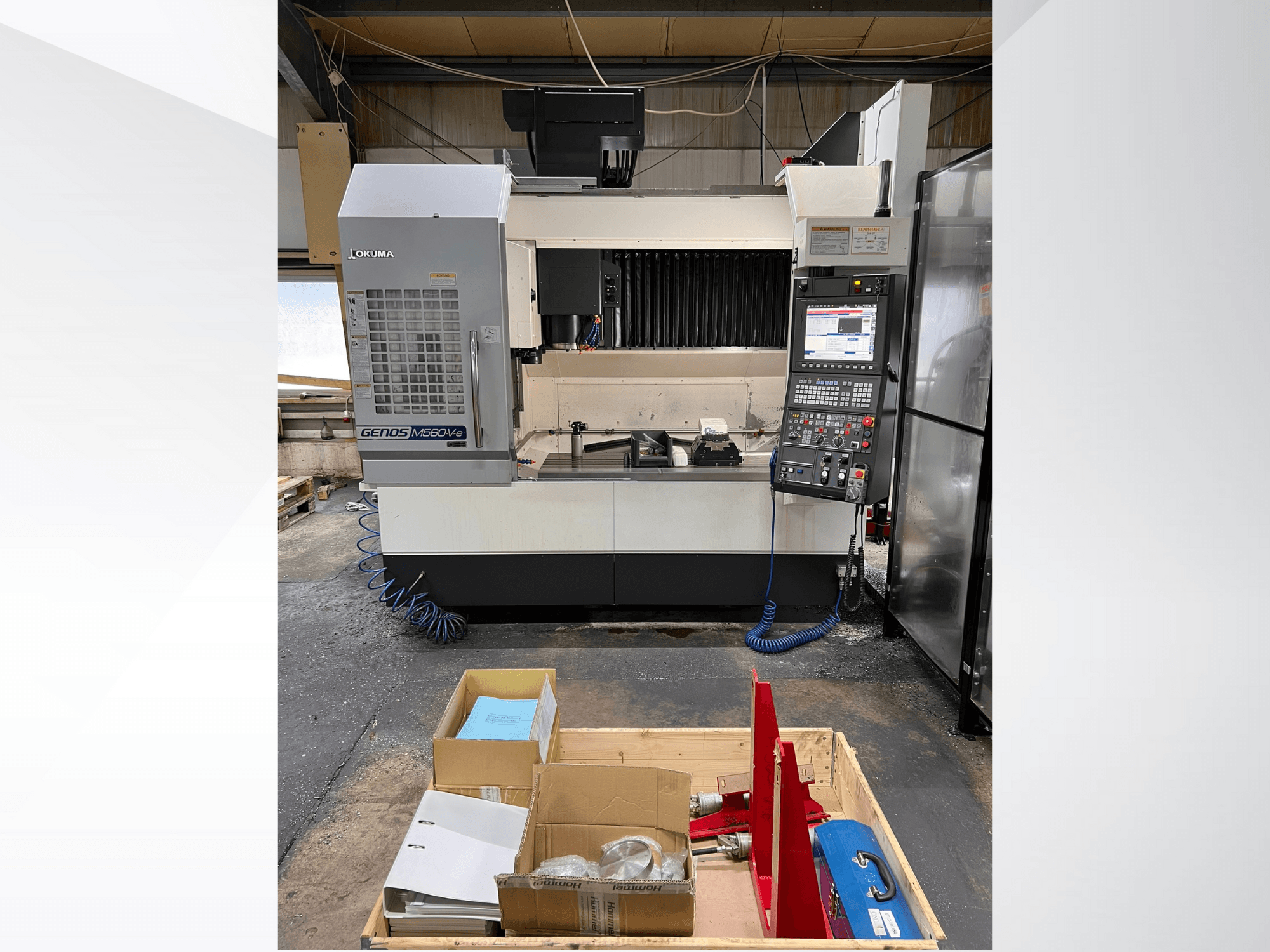 Okuma GENOS M460V-5 vertikal fleroperationsmaskin, framifrån, med synlig kontrollpanel och verktyg på arbetsbordet.