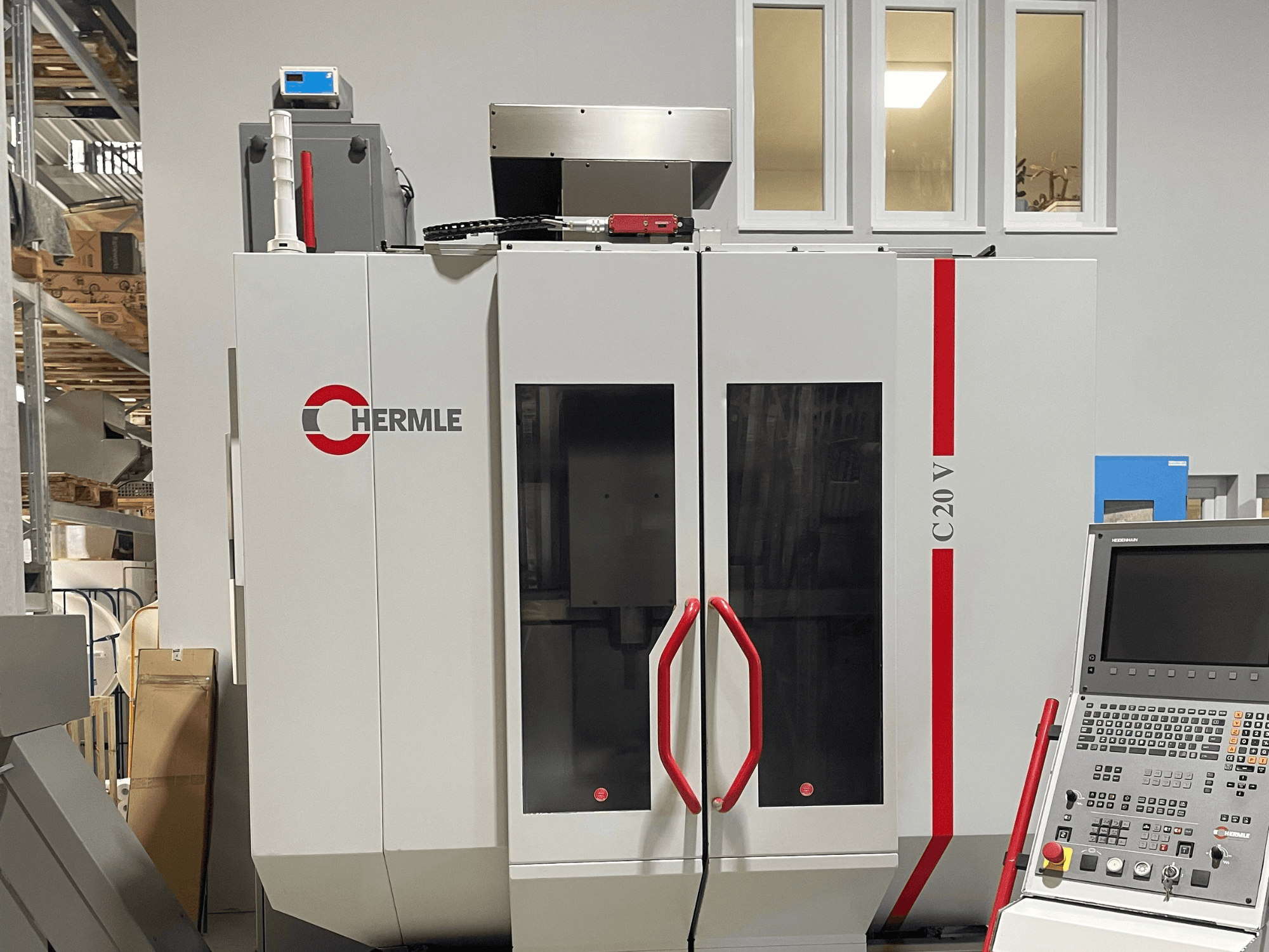 CNC-maskin Chermle C20 V, framifrån, med kontrollpanel och röda handtag; industriell design med stora glasdörrar.