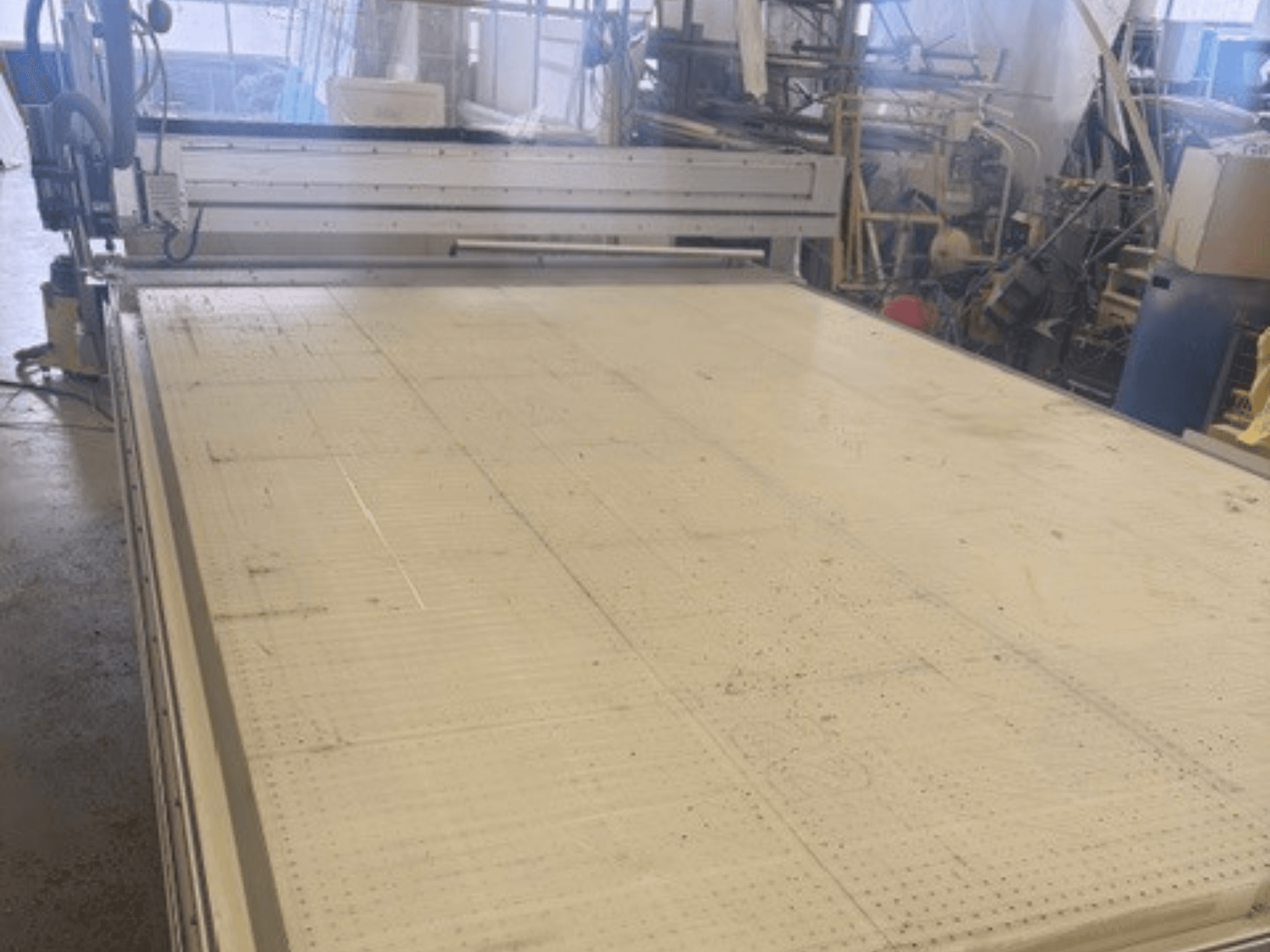 Stor skärmaskin med plan yta, med ram och styrskena; sedd från en vinkel i en verkstadsmiljö.