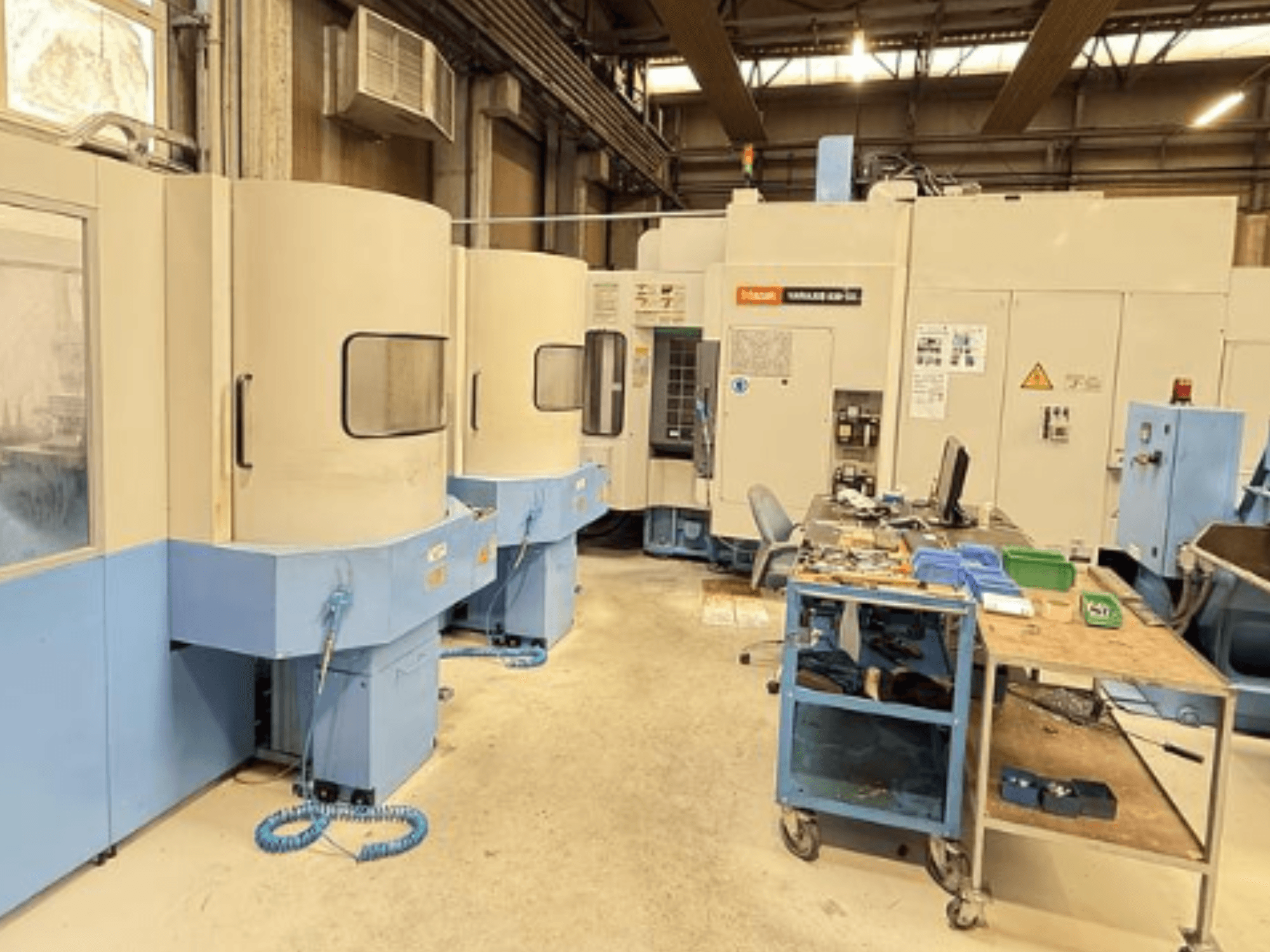 Mazak Variaxis 630-5X vertikal fleroperationsmaskin i en verkstad, framifrån med kontrollpanel och förvaringsutrymme för verktyg.