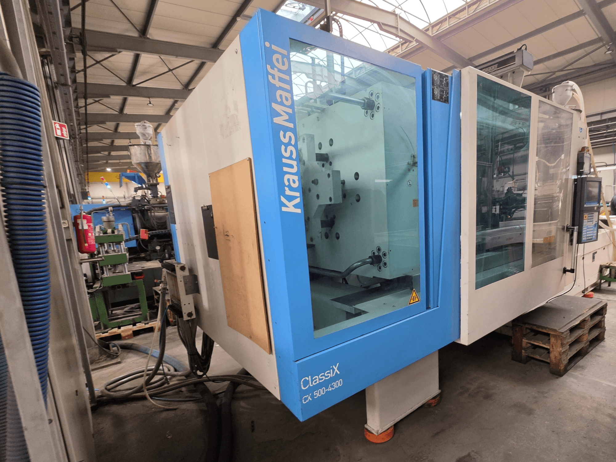 Krauss Maffei 500-4300 CX hydraulisk formsprutningsmaskin, sidovy, visar kontrollpanel och driftskomponenter.