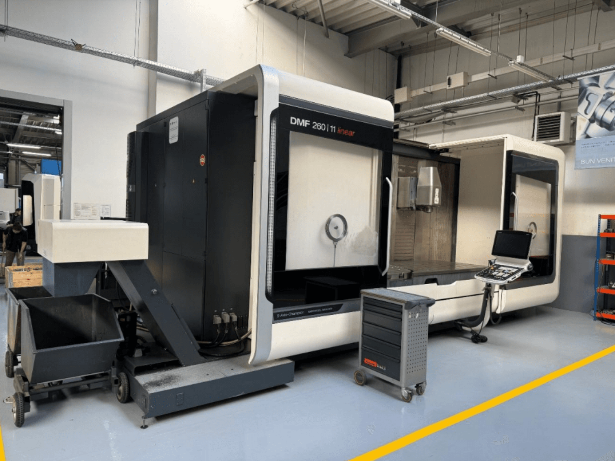 DMG MORI DMF 260 Linjär fräsmaskin visad framifrån, med en verktygskontrollpanel och en mobil verktygsvagn i närheten.