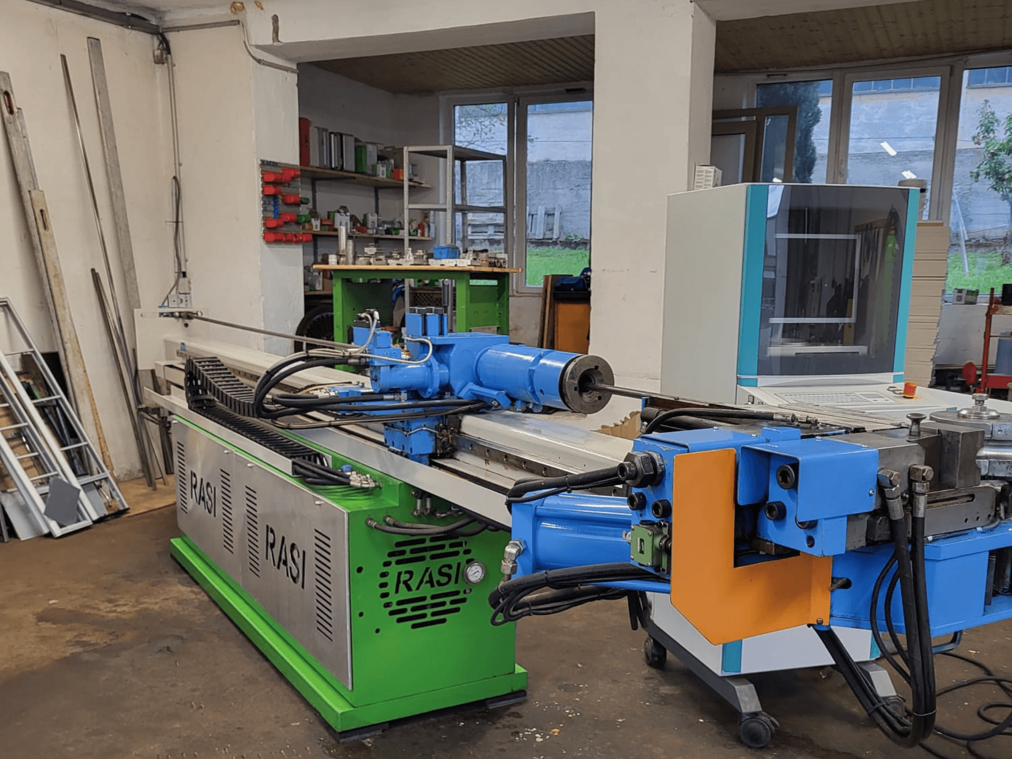 Rasi S 80.6 L G-V3C50 verktygsmaskin i verkstadsmiljö, sidovy som visar blå och gröna komponenter och kontrollpanel.