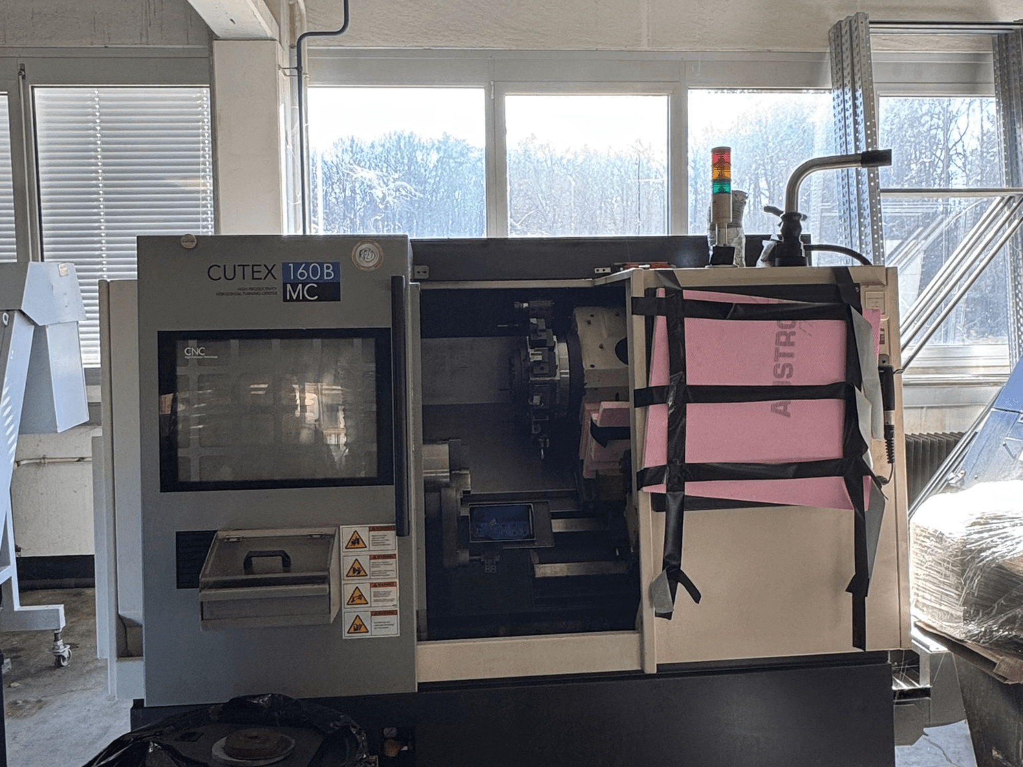 Framifrån sett av den horisontella svarven HWACHEON CUTEX 160 B VDI med kontrollpanel och kylvätsketank, utrustad med en säkerhetslampa.