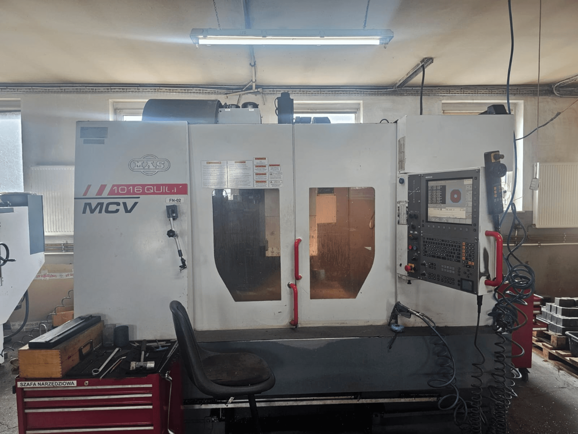 MVS MCV 1016 QUILL CNC-maskin, framifrån, med kontrollpanel, verktygslåda och arbetsyta med verktyg.