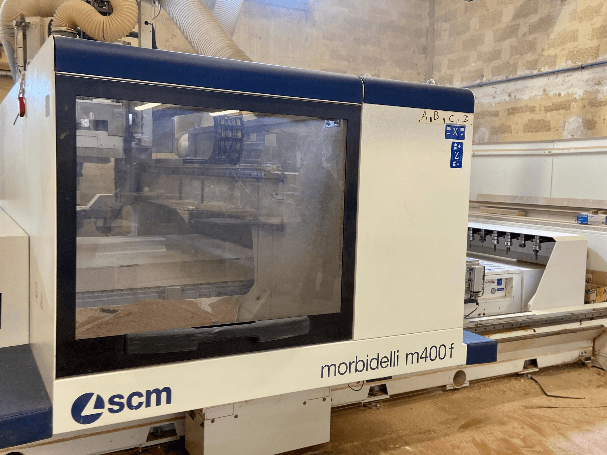 SCM Morbidelli M400F CNC-maskin, vy framifrån, med kontrollpanel och synligt sågspån på golvet.