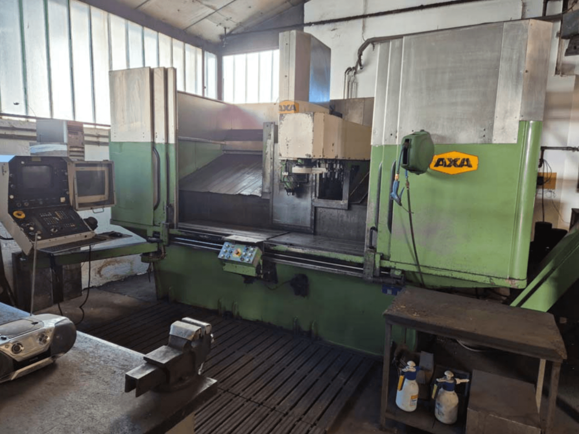 AXA VSC-2M vertikal fleroperationsmaskin, vy framifrån, med kontrollpanel och arbetsområde med skärverktyg och rengöringsutrustning.