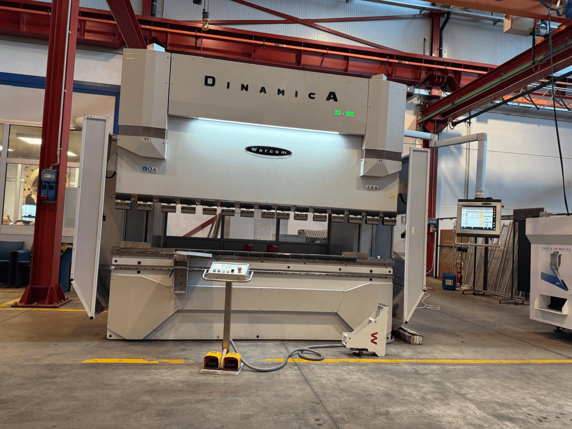 Dinamica Warcom hydraulisk kantpress, vy framifrån. Utrustad med kontrollpanel och flera verktygsstationer för precisionsbockning.