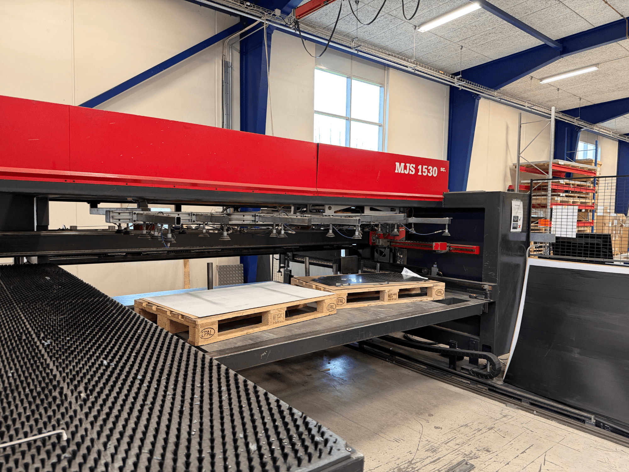 MJS 1530 CNC-maskin i en verkstad, framifrån, med en träpall som håller en metallplåt på en upphöjd plattform.