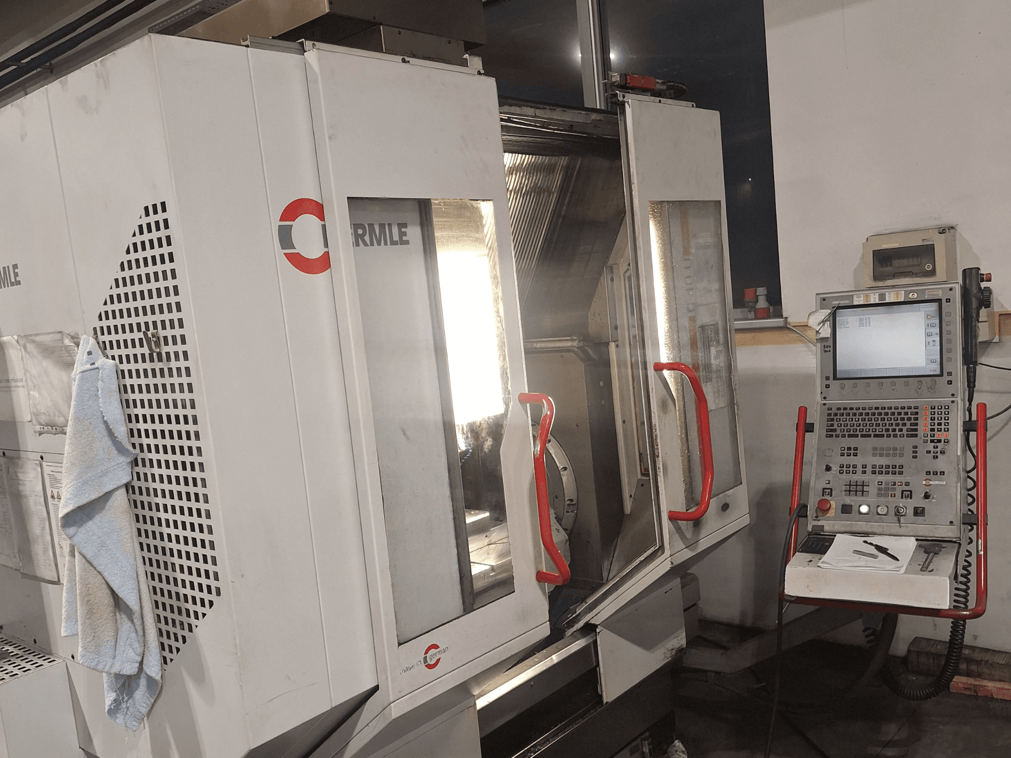 CNC-maskin av märket Cormile, framifrån med delvis öppna dörrar och kontrollpanel med skärm och knappar.