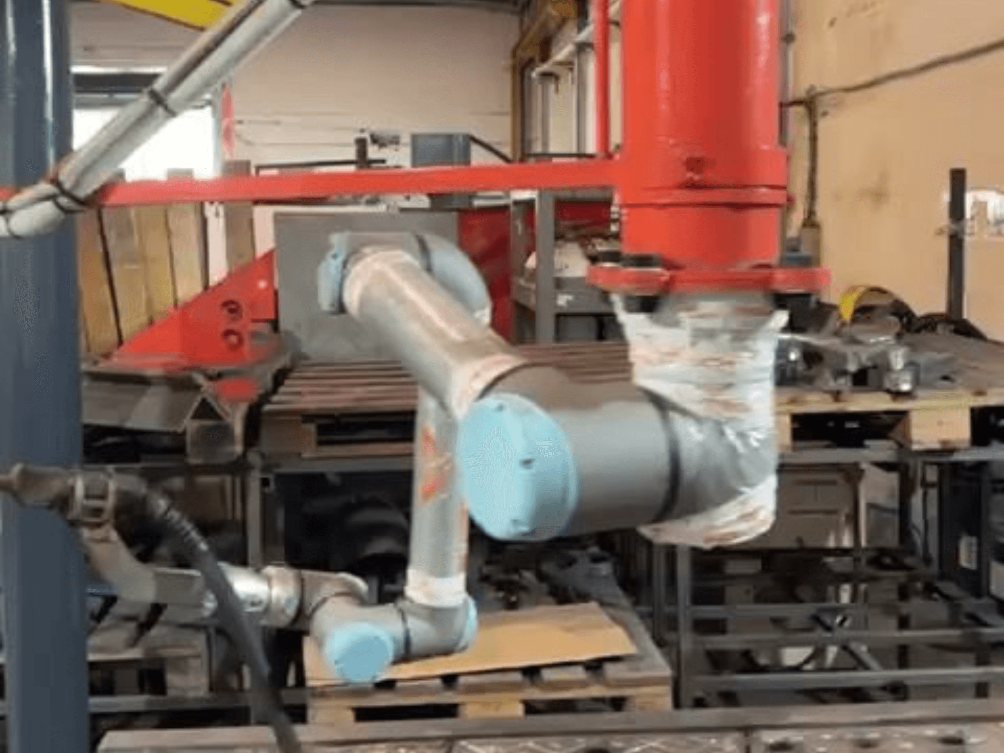 En samverkande robot av typen Universal Robots UR10e i en verkstad; sidovy som visar armens och ledernas rörelser i närheten av maskinerna.