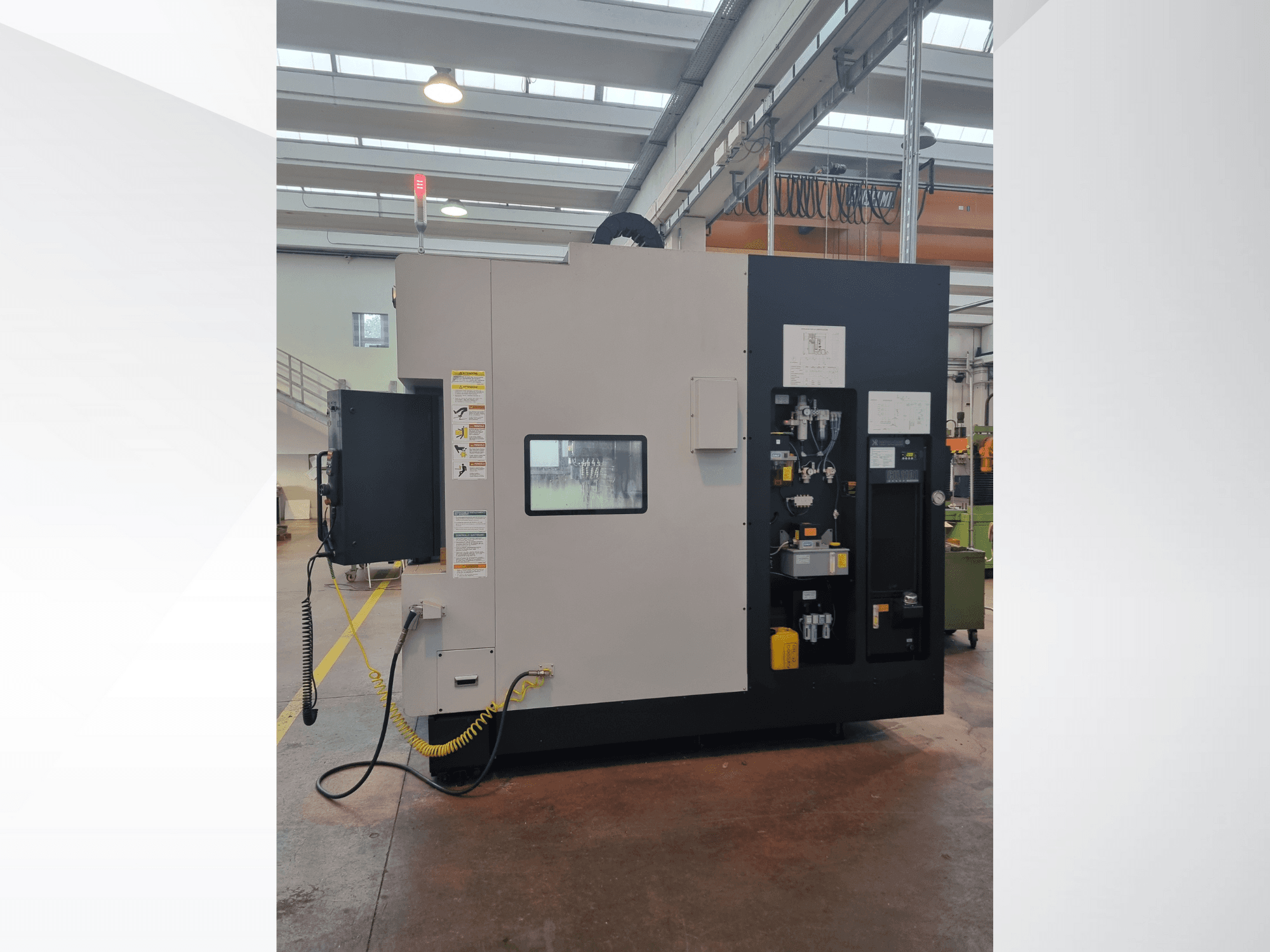 Industrimaskin från sidan, har en kontrollpanel med knappar, indikatorer och en säkerhetsvarningsetikett.