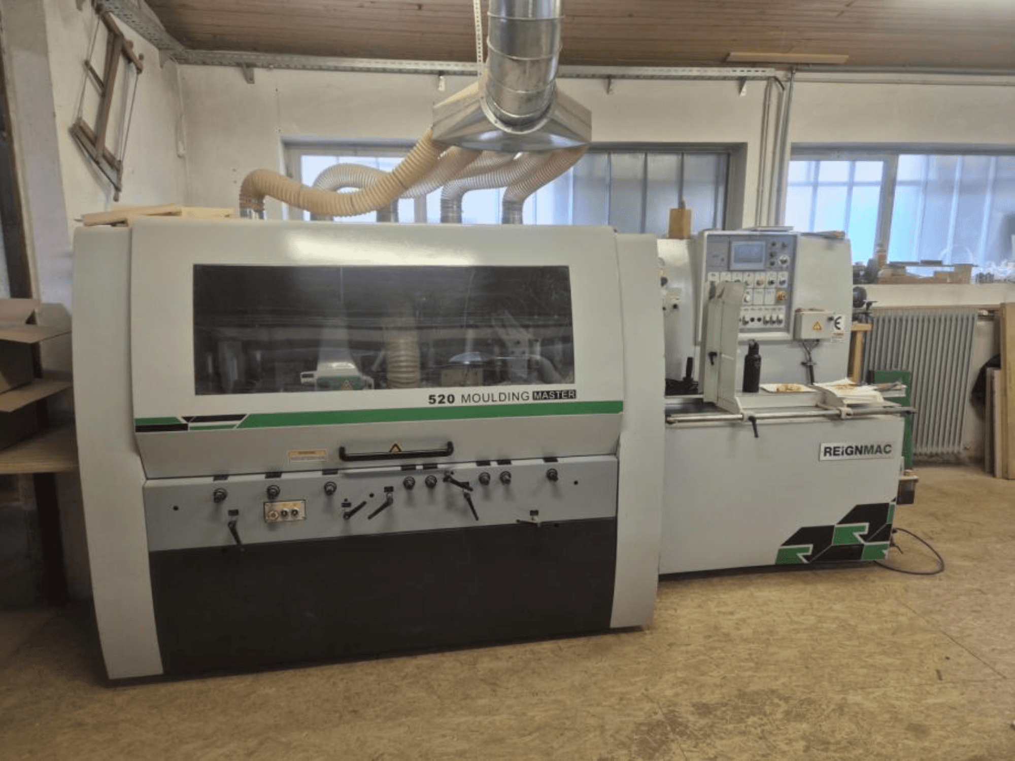 Framsida av REIGNMAC 520 MOULDING MASTER hyvel, med kontrollpanel, matarvalsar och dammutsugningssystem.