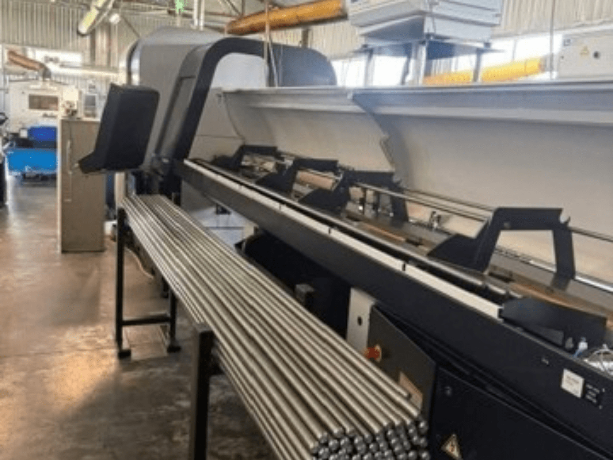 Framifrånvy av den schweiziska svarven TORNOS EvoDECO 32 med metallstänger uppradade bredvid, vilket ger en bild av en industriell arbetsmiljö.